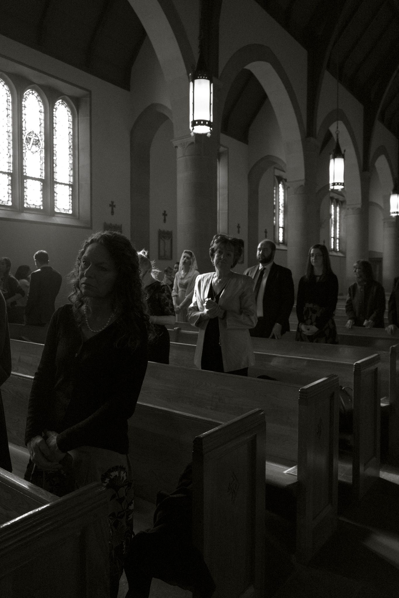 Black and white photo of wedding guests seated in church pews during ceremony.