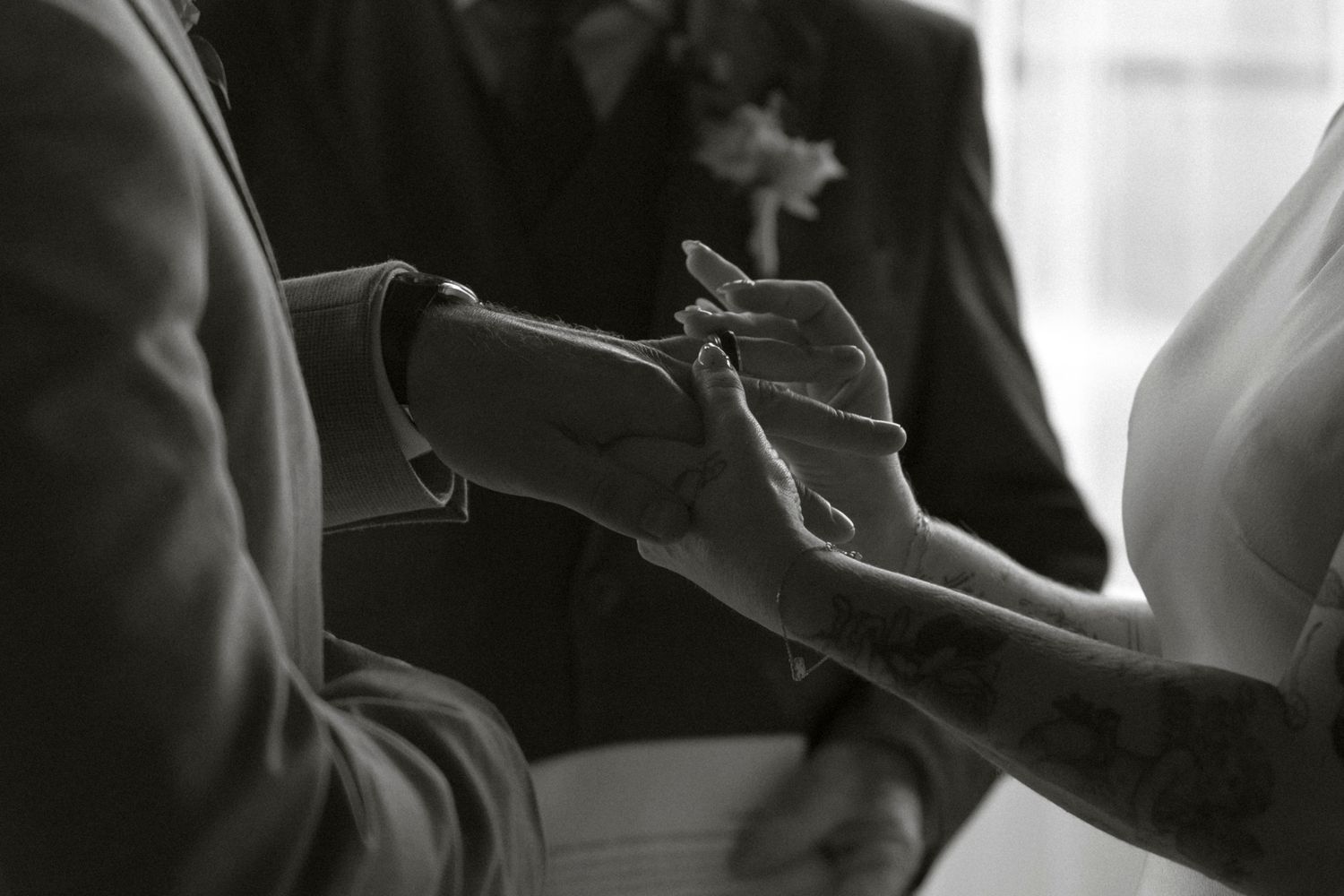 Silhouetted figures at an intimate wedding ceremony against bright window light.