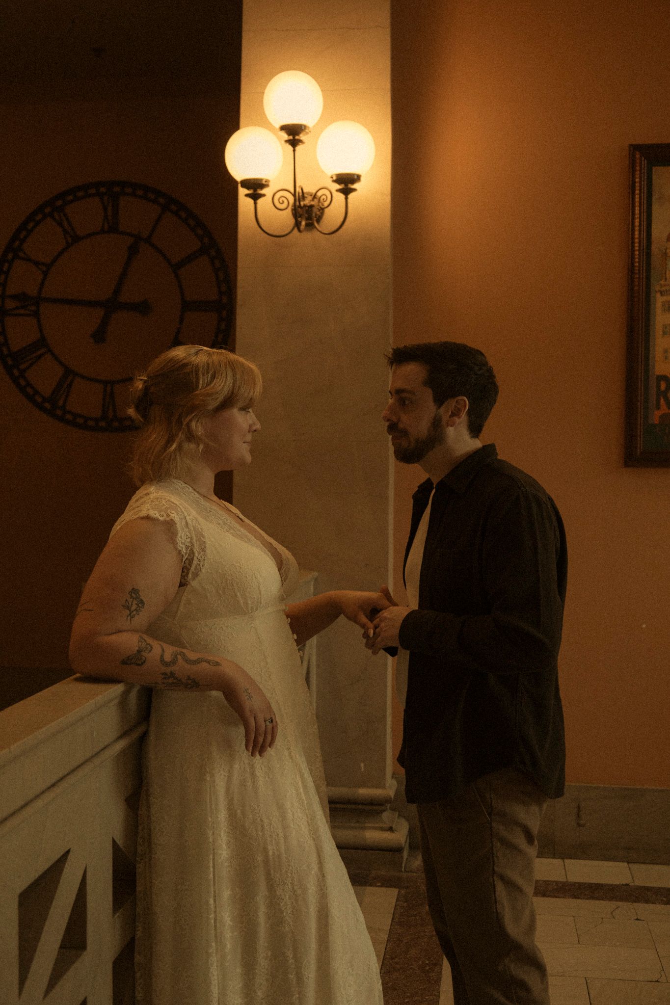 A couple in wedding attire shares an intimate moment in a warmly lit indoor setting with vintage decor.