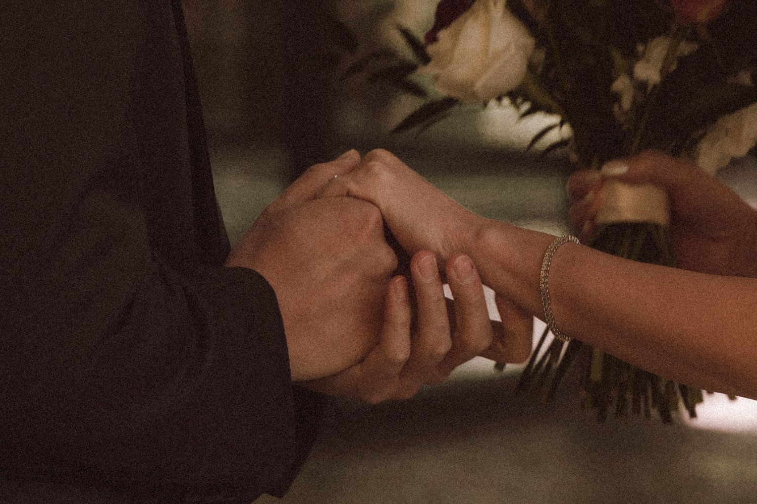 Close-up view of hands signing paperwork with a pen on a wooden desk surface.