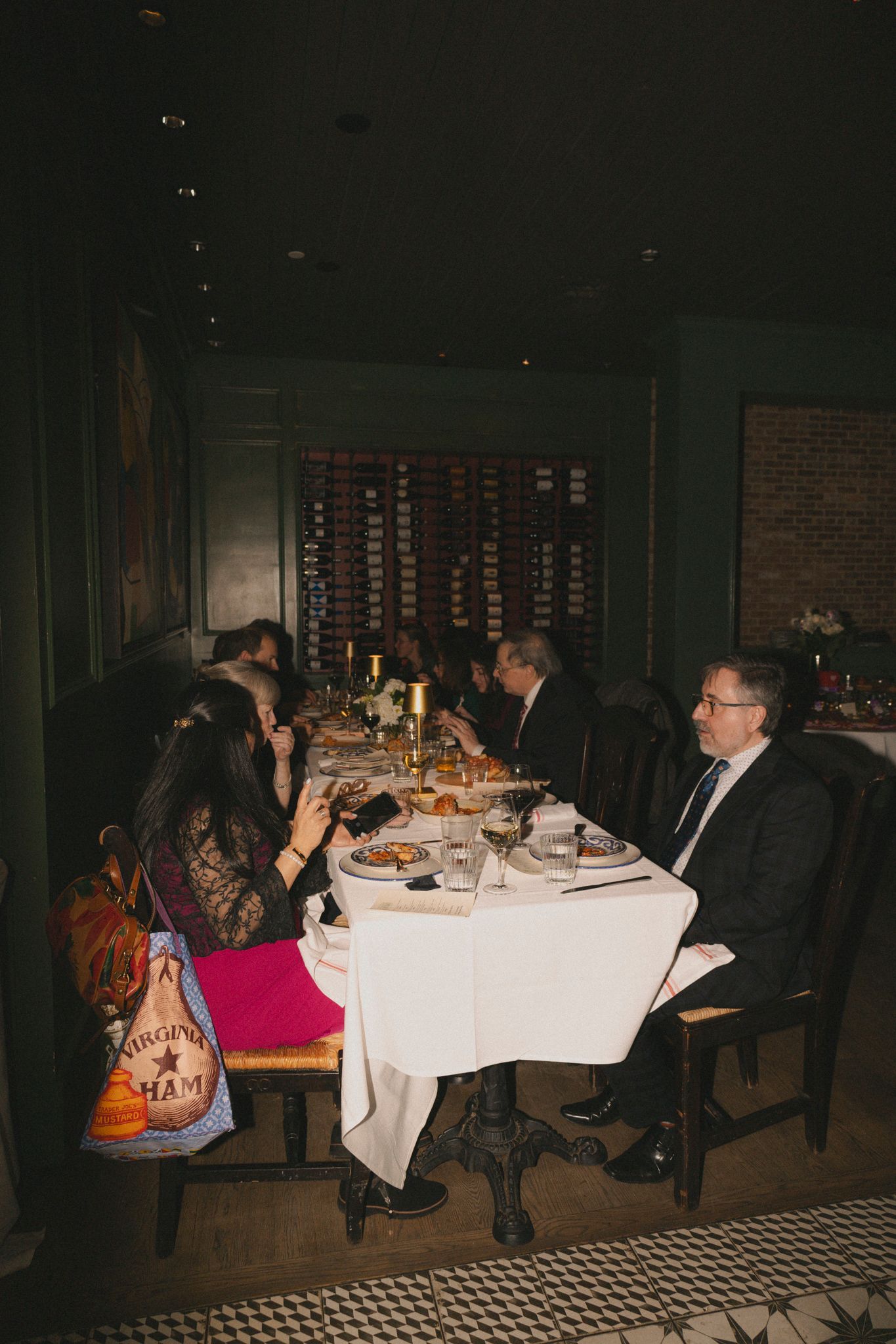 Guests seated at a long dining table during an intimate wedding reception dinner in a dimly lit restaurant.