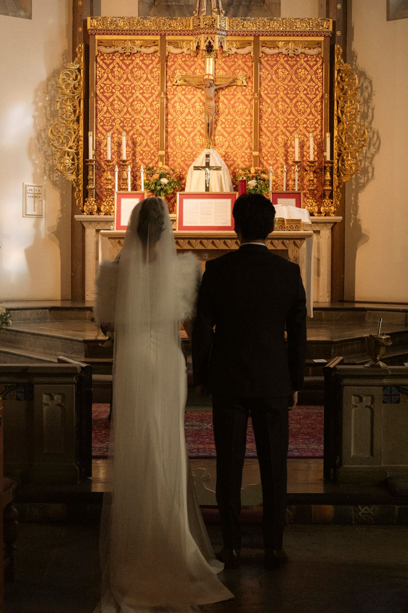 Bride and groom stand before ornate golden altar during traditional church wedding ceremony.