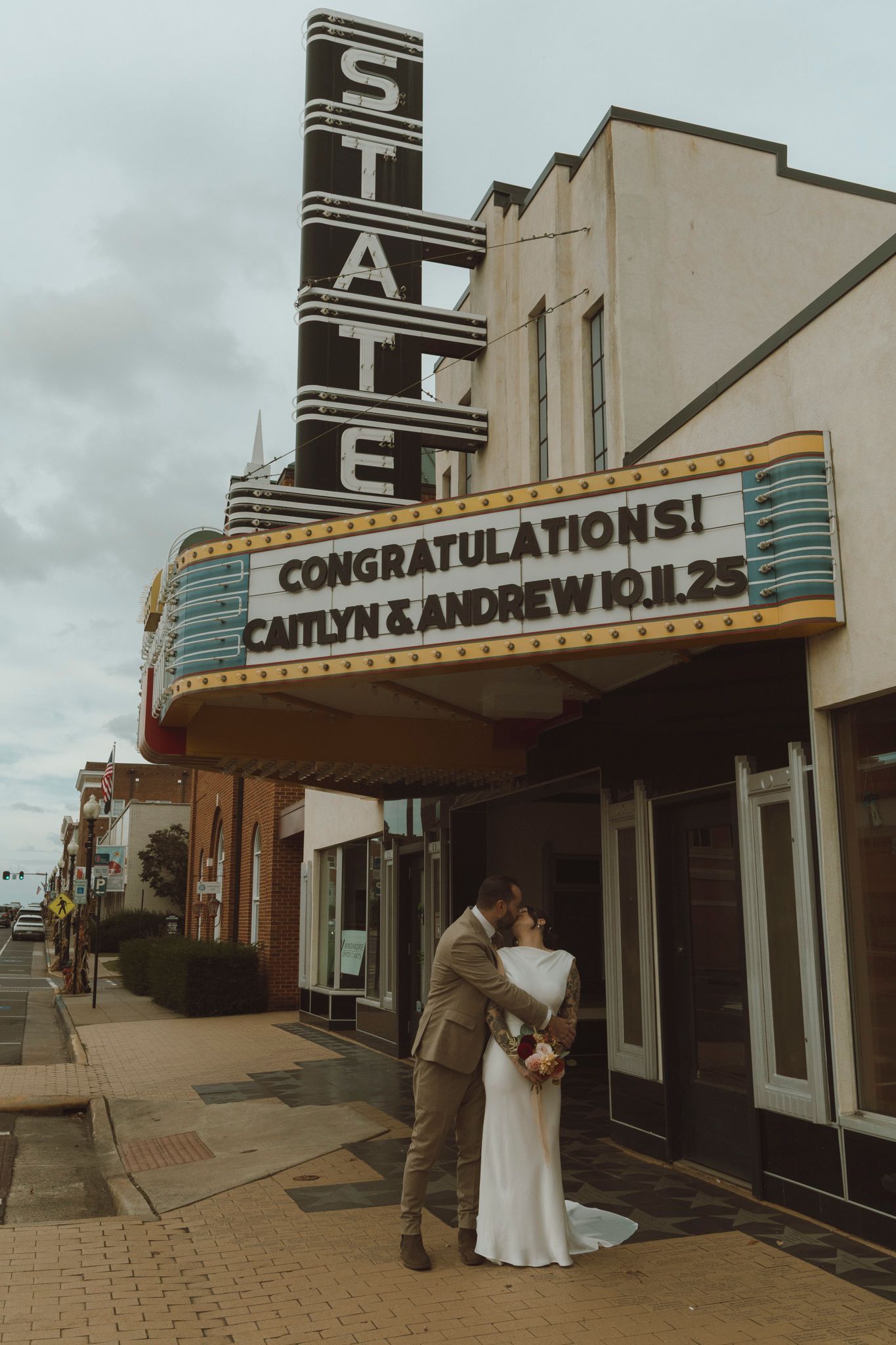 A vintage theater marquee displays wedding congratulations outside a historic building.