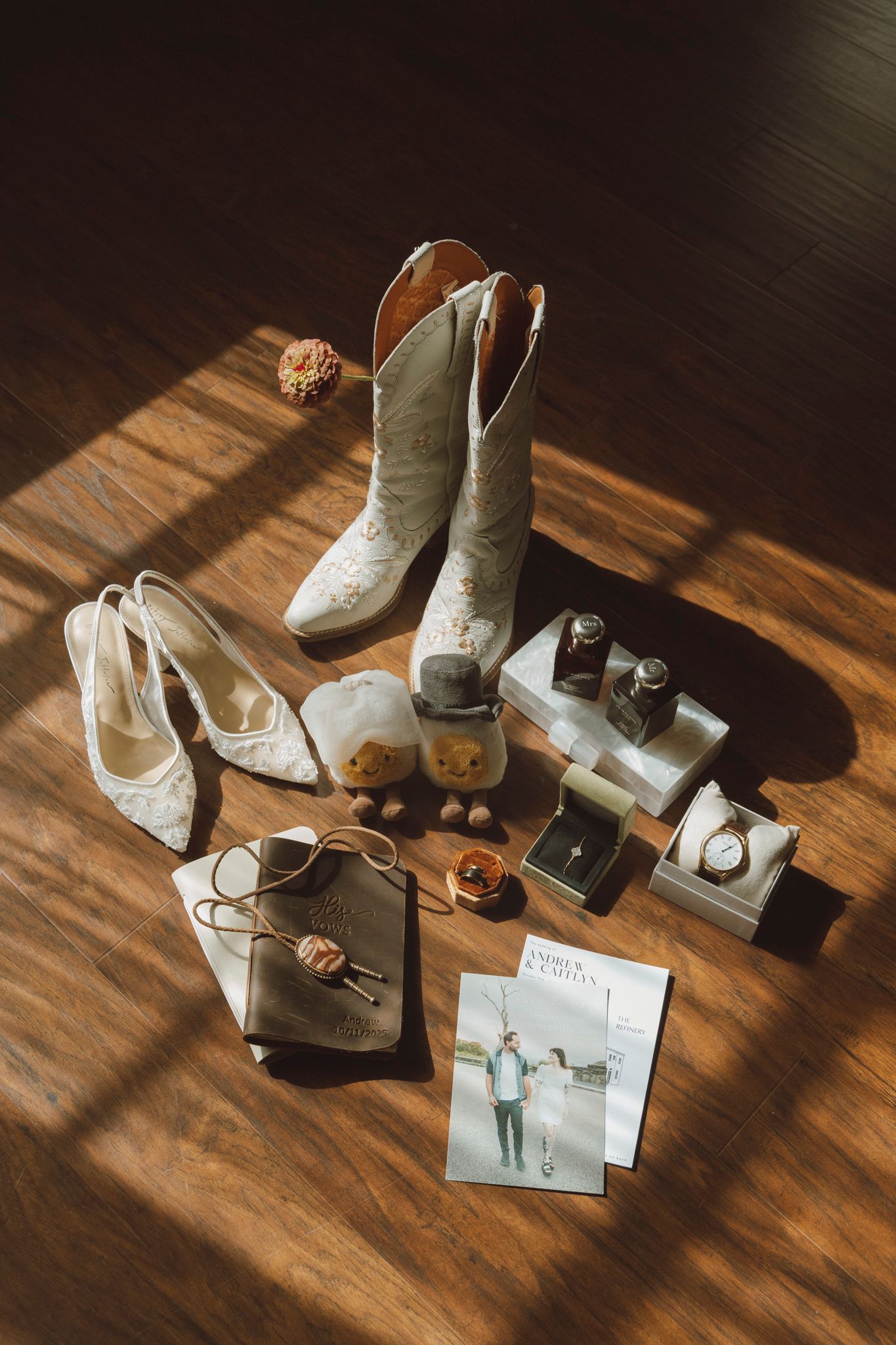White boots and accessories arranged artistically on a wooden floor with dramatic natural lighting and shadows.