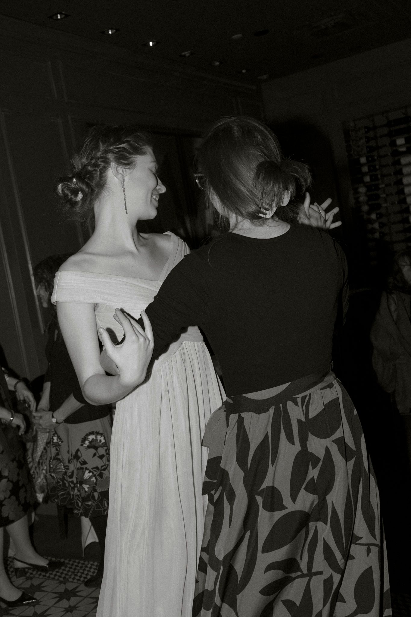 Black and white photo of two women dancing together at a wedding reception in elegant formal wear.