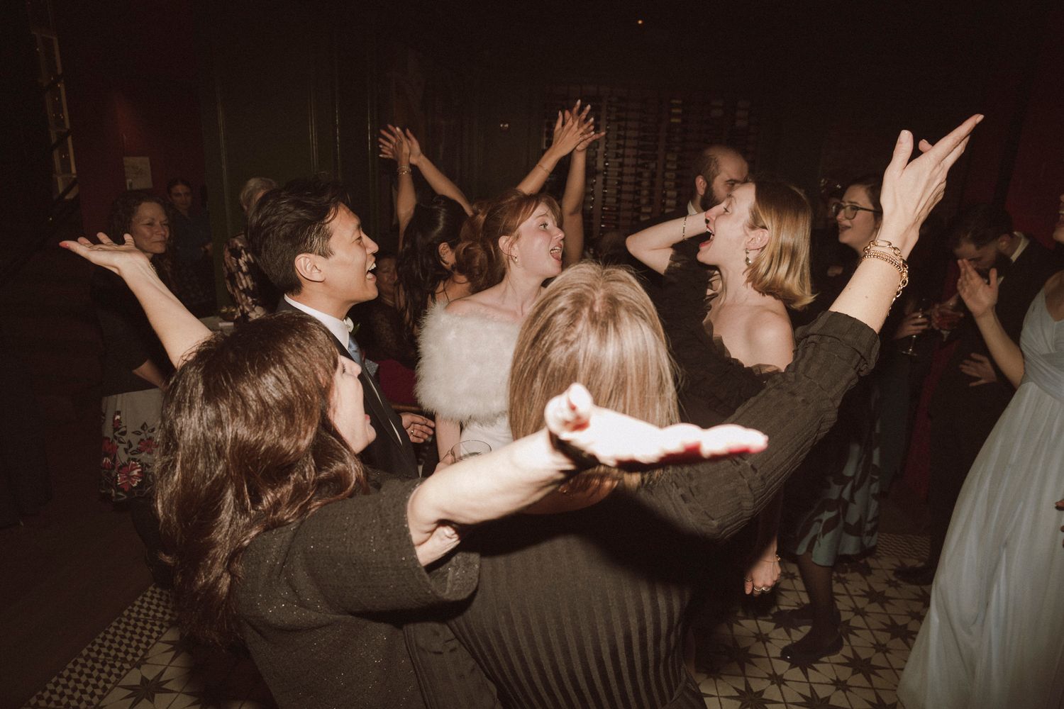 Joyful wedding guests dancing together on the dance floor at a lively wedding reception party.