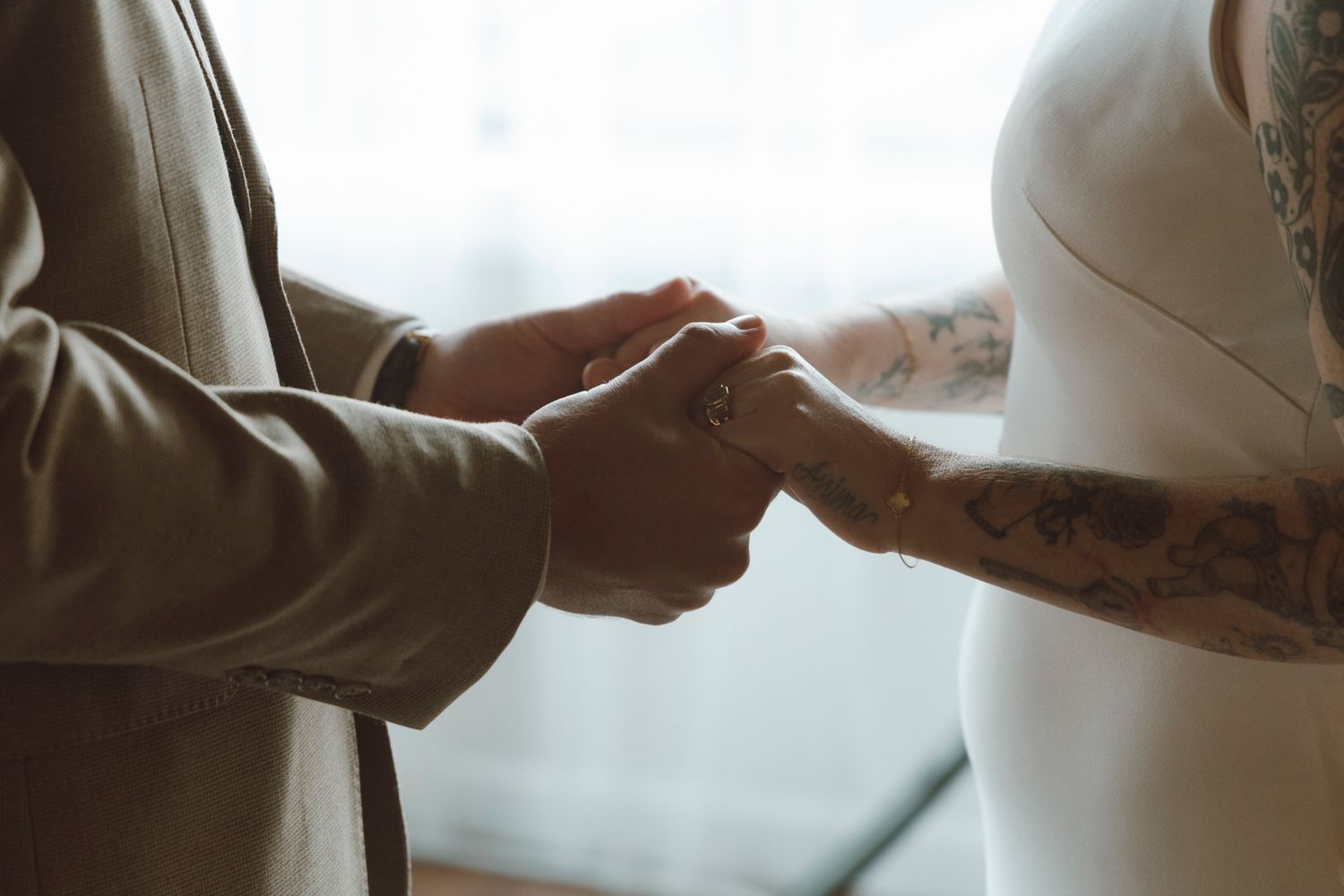 Two hands clasped together in a tender moment against a light background.