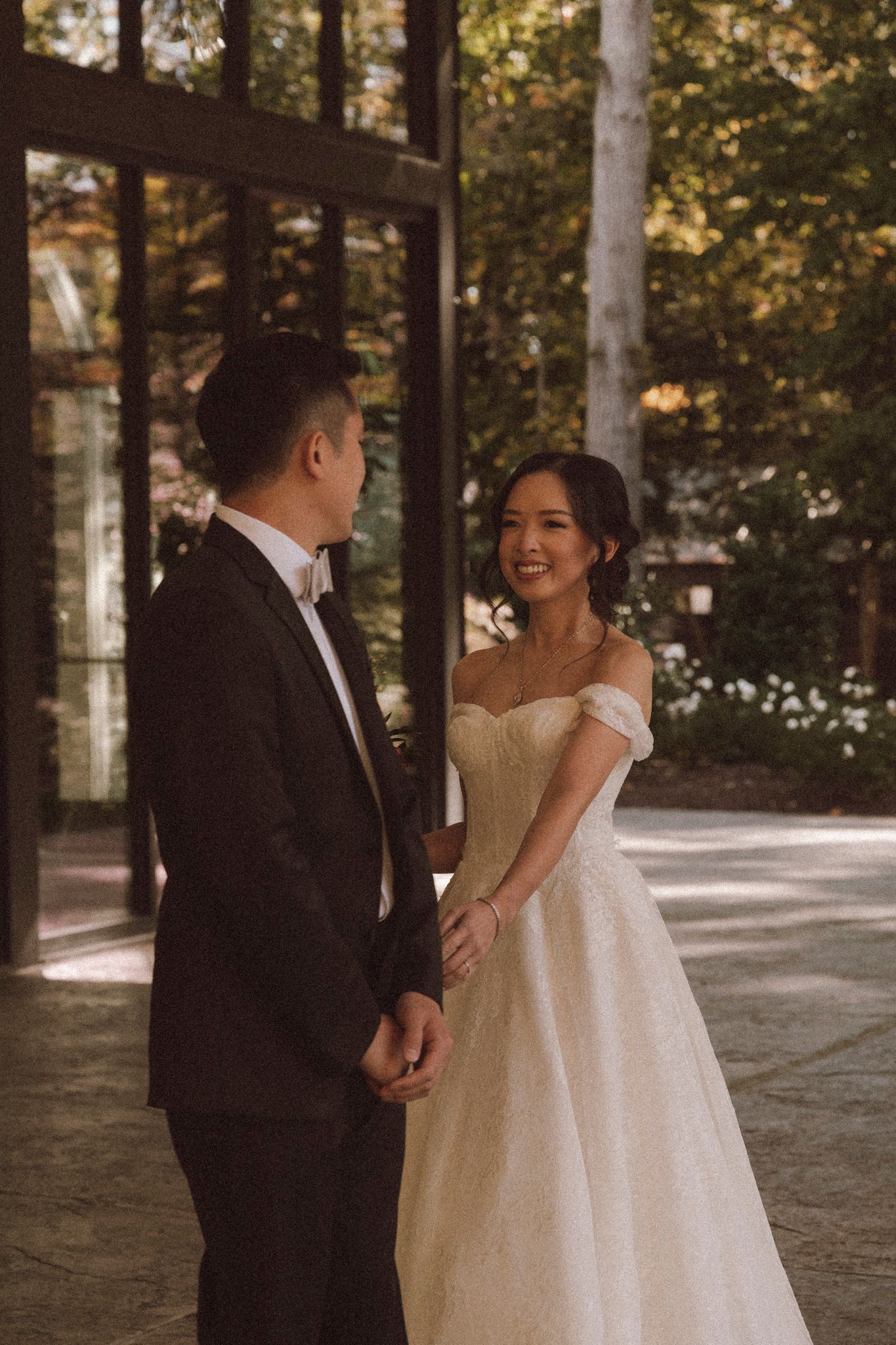 A couple shares a joyful first look moment during their wedding ceremony in a sunlit outdoor setting.
