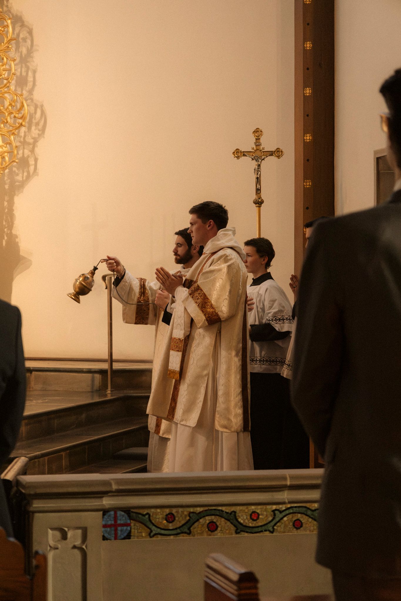 Catholic priest swinging a thurible with incense during a traditional wedding Mass at the altar.