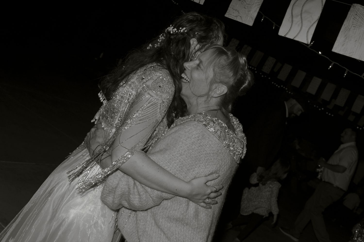 A wedding couple shares a romantic kiss during their first dance on a dimly lit dance floor.