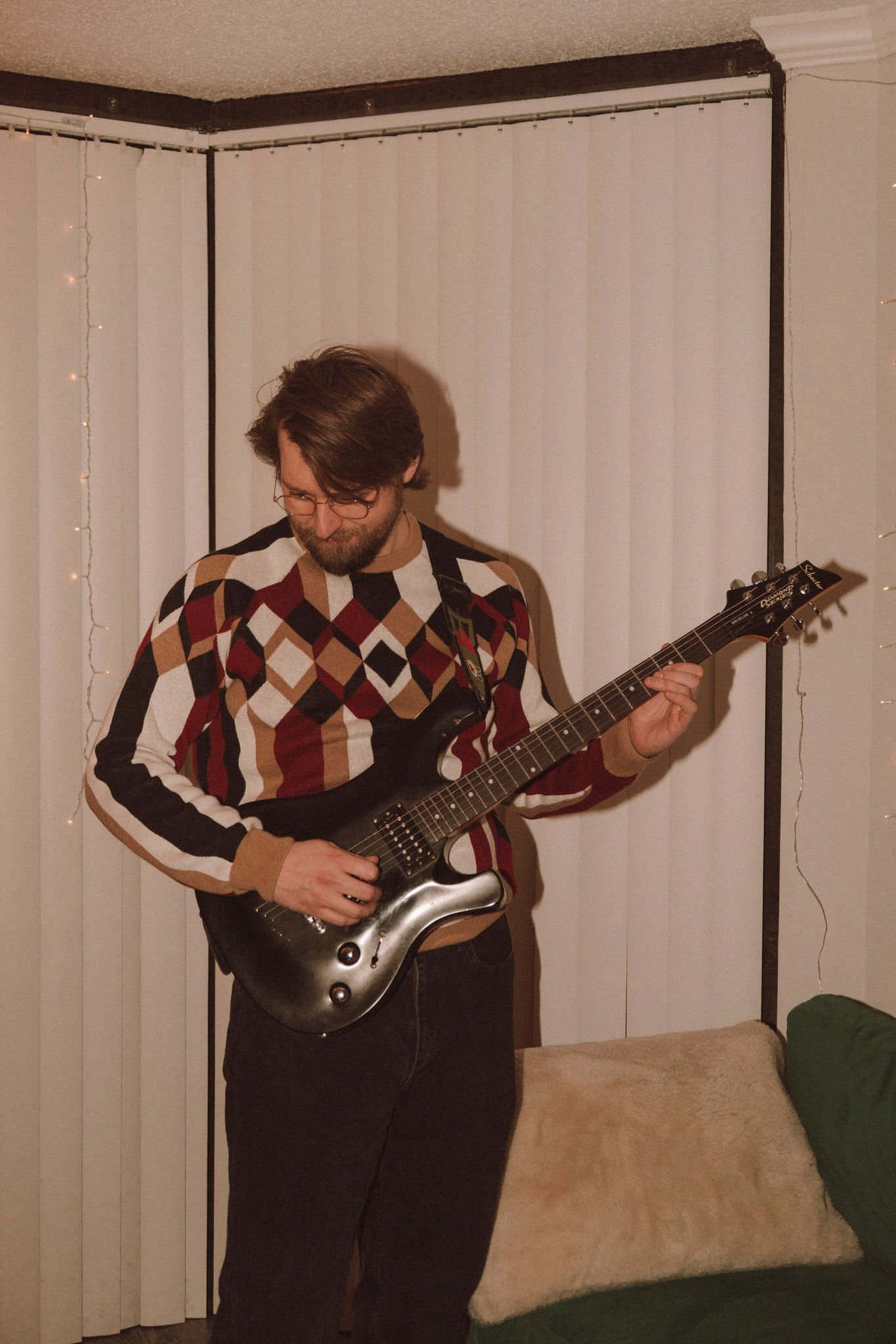 A sequence of five photos showing someone playing an electric guitar while wearing an argyle sweater vest.