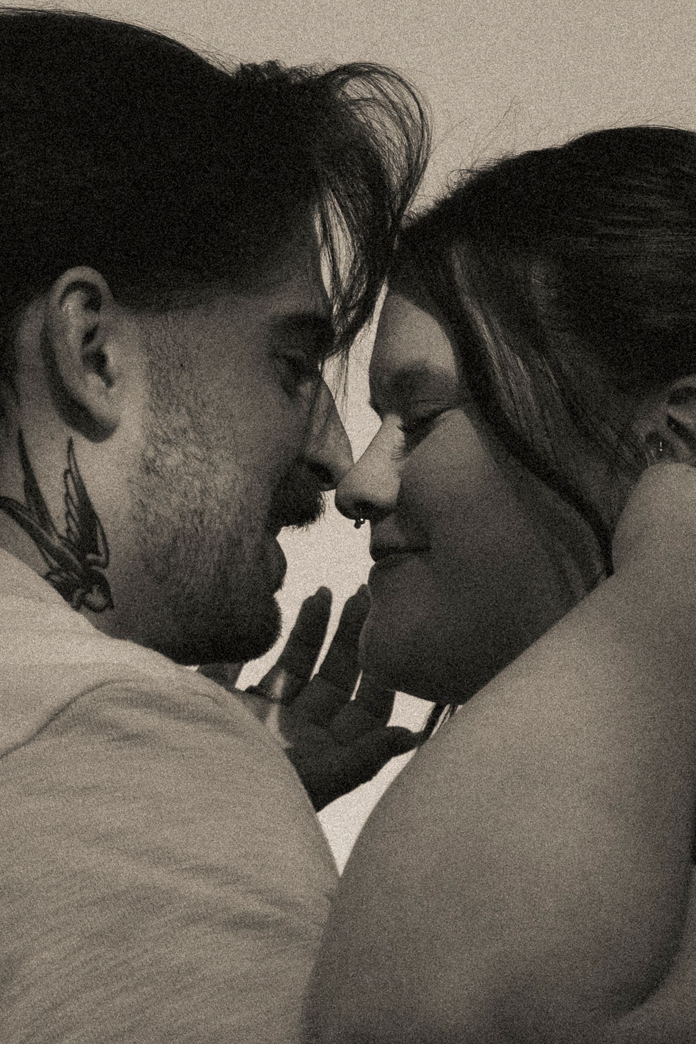 Romantic black and white close-up of couple almost kissing with foreheads touching.