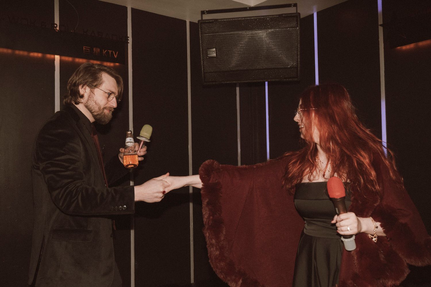 People dancing together at a dimly lit nightclub or party venue with red lighting effects.