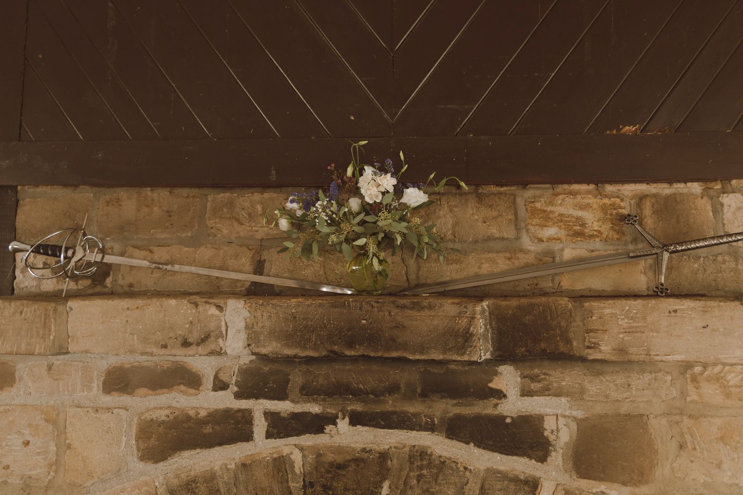 A rustic stone wall with exposed wooden beams and natural lighting creates a warm, textural architectural detail.
