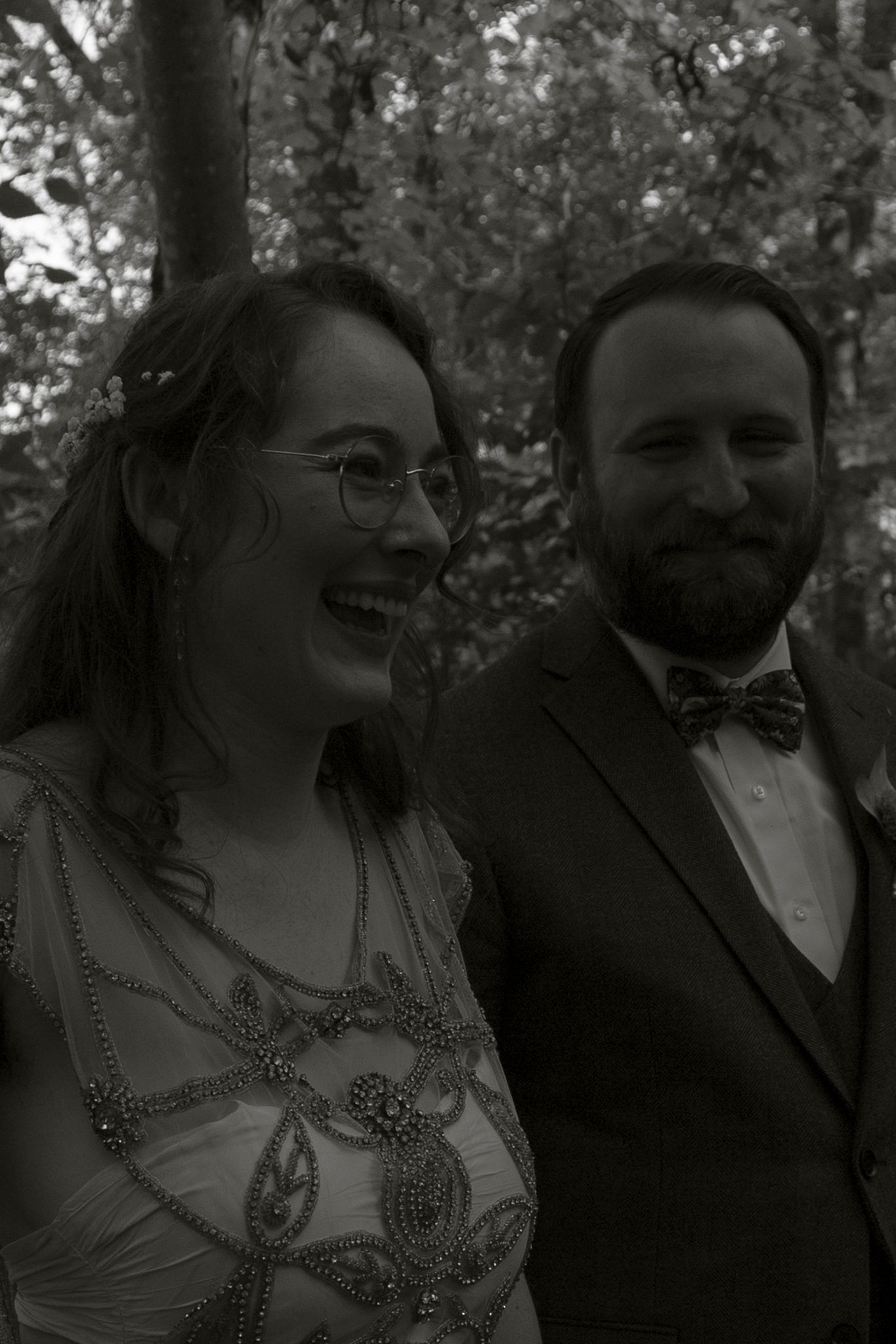 A couple shares a joyful moment together outdoors in black and white photography.