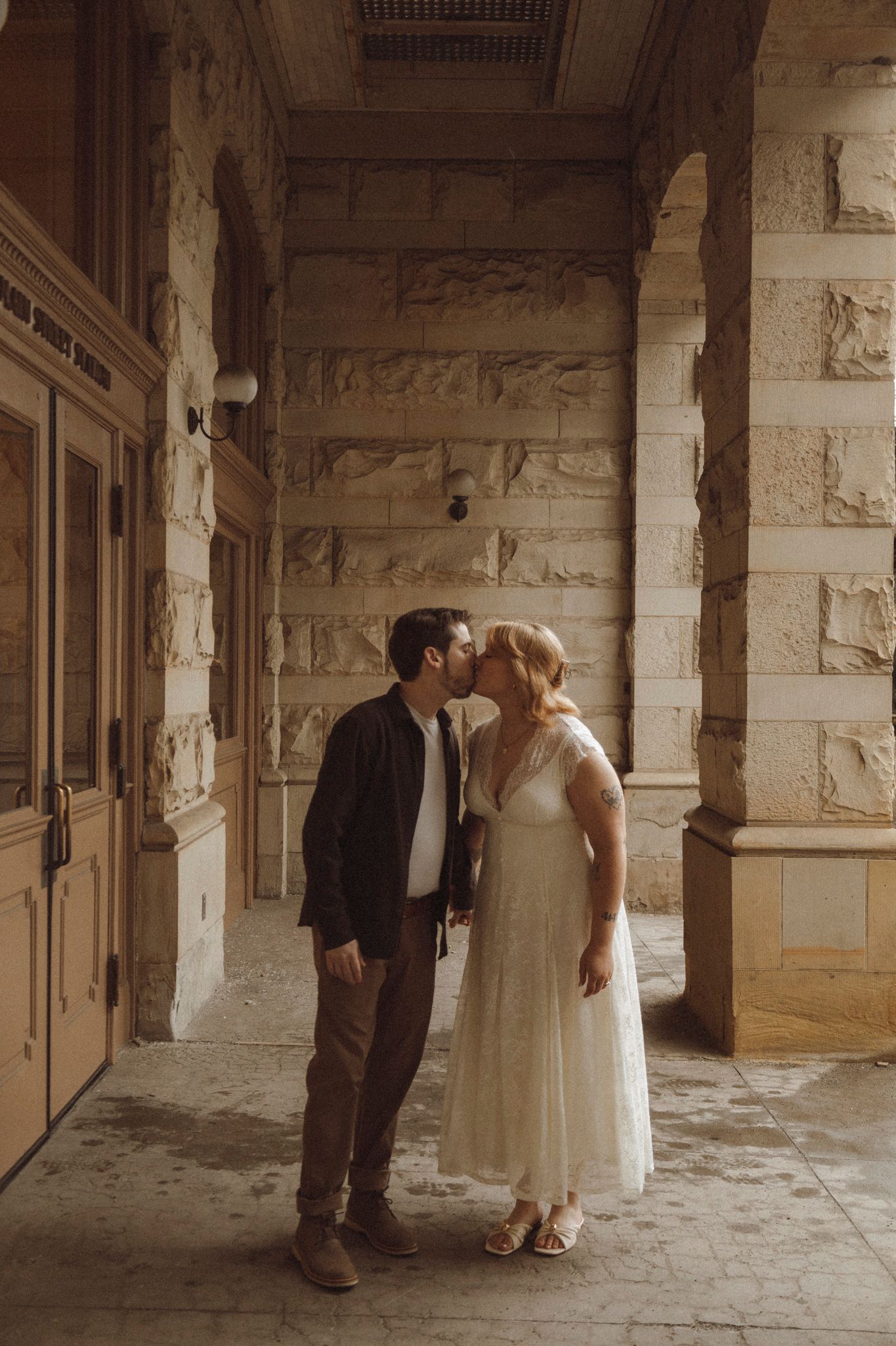 A couple shares an intimate moment in a vintage stone archway corridor with warm lighting and romantic ambiance.