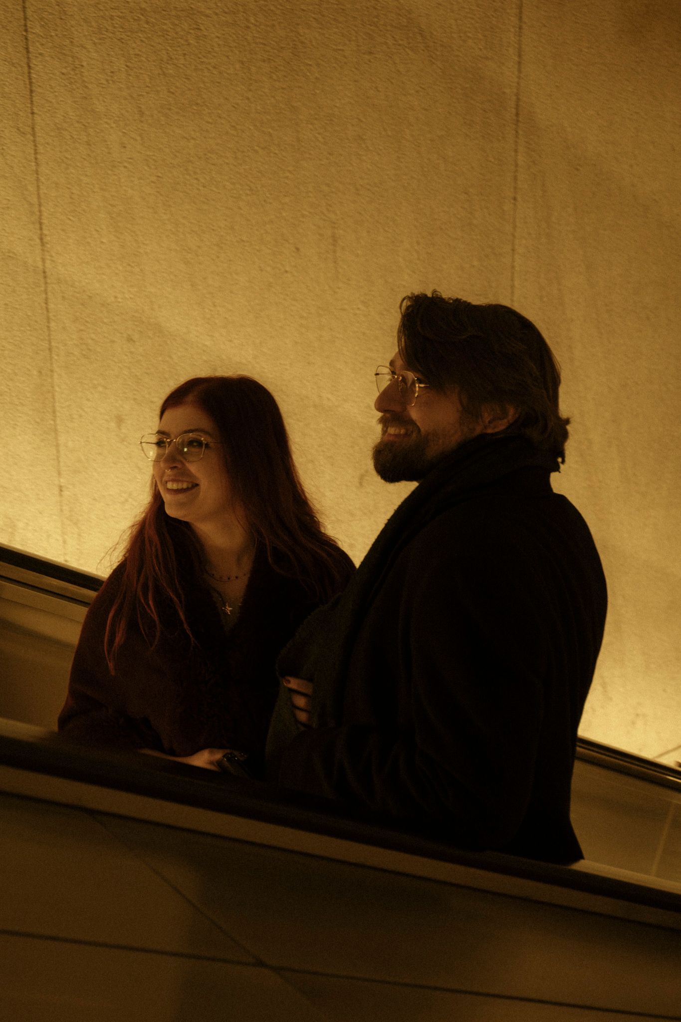 A sequence of sepia-toned images shows two people laughing together in a dimly lit space.