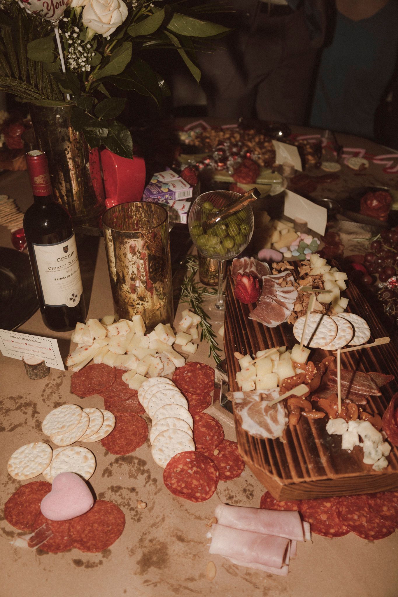 Elegant wedding charcuterie board with salami, cheese, crackers, olives, and red wine bottle.