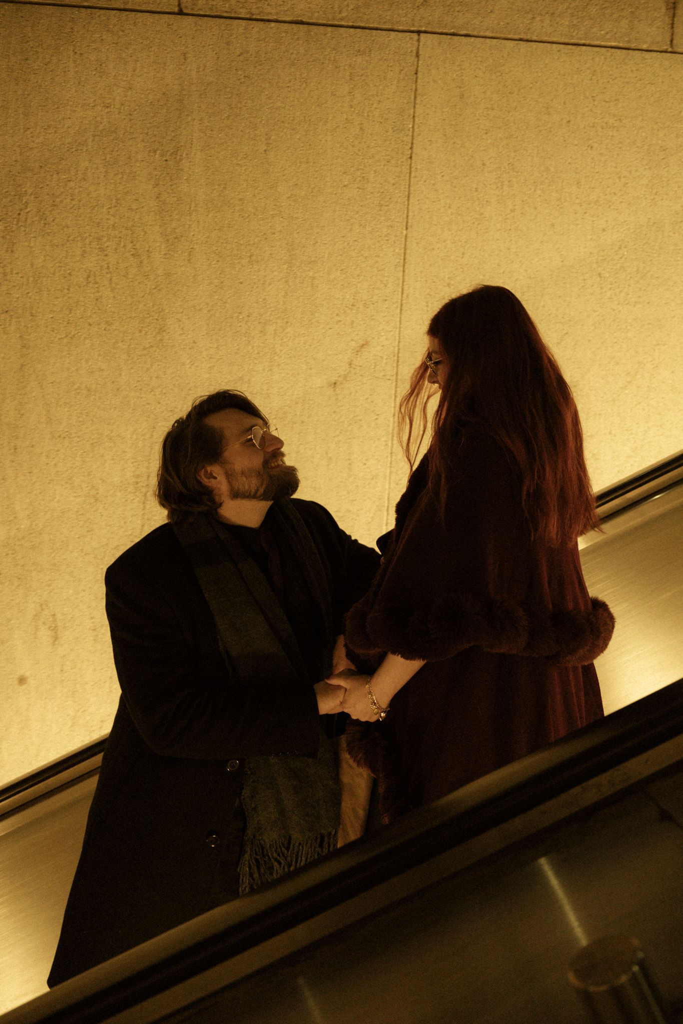 A couple shares an intimate moment on a dimly lit escalator in a sepia-toned sequence of photographs.