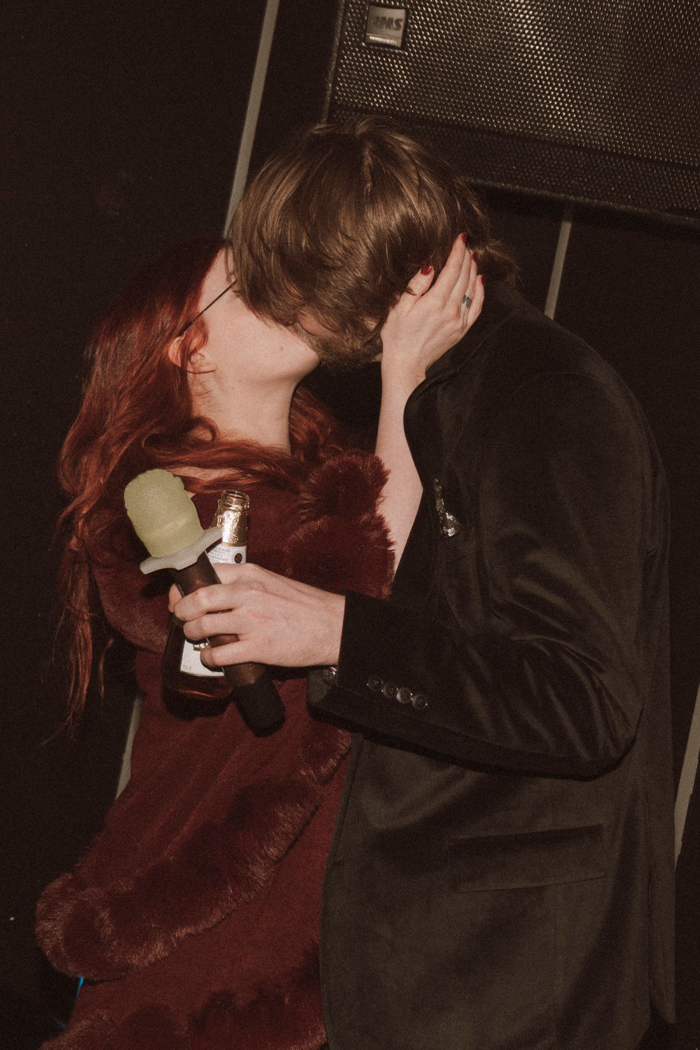 Two people sharing an intimate moment in a dimly lit setting with one person wearing a black jacket.