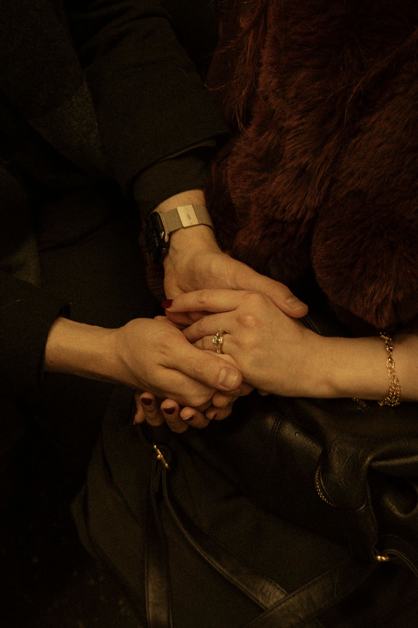 Close-up sequence of hands clasping and unclasping in dramatic lighting against dark background.
