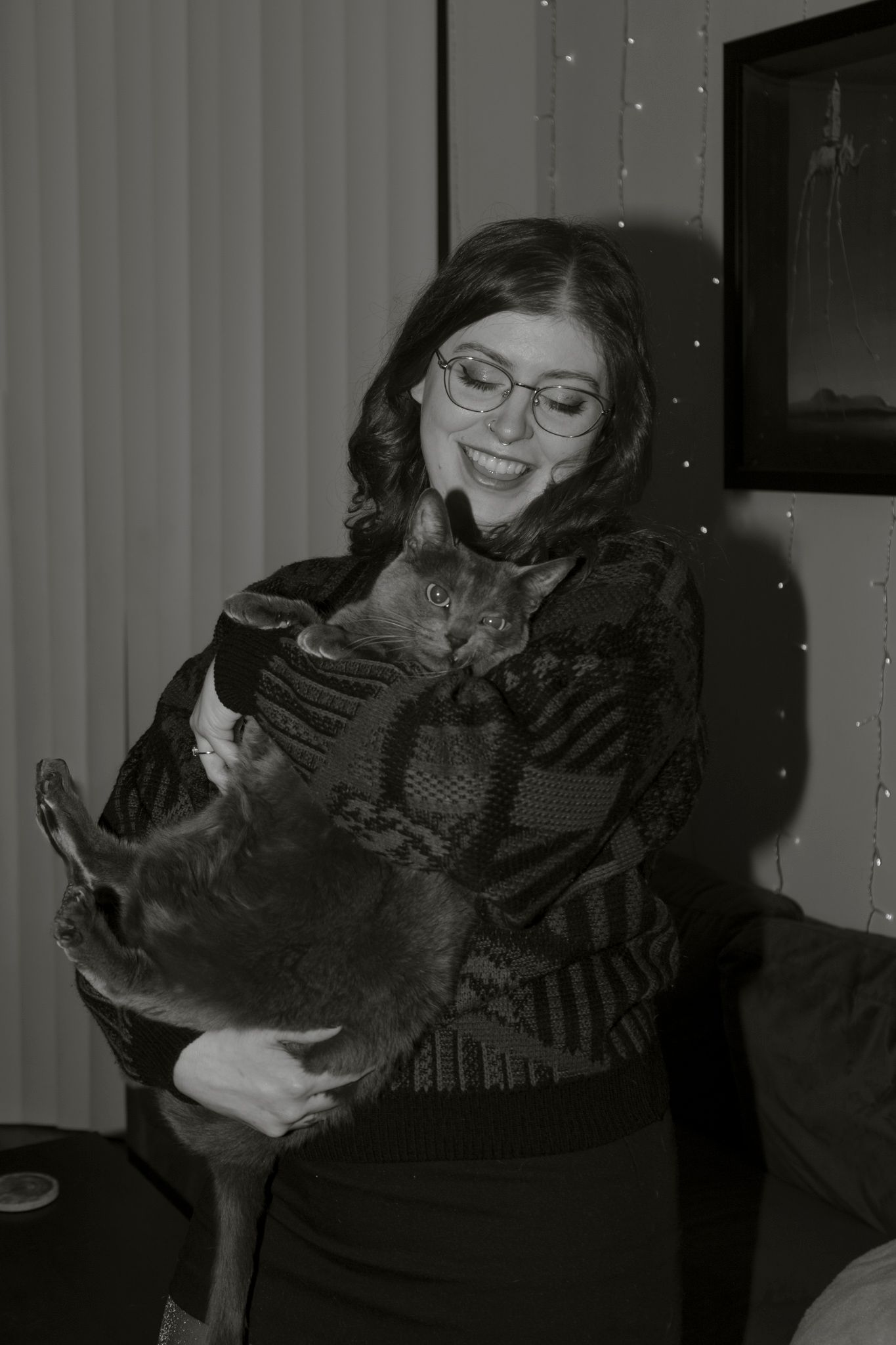 A person in dark clothing holds and interacts with a black cat in a series of candid indoor photos.