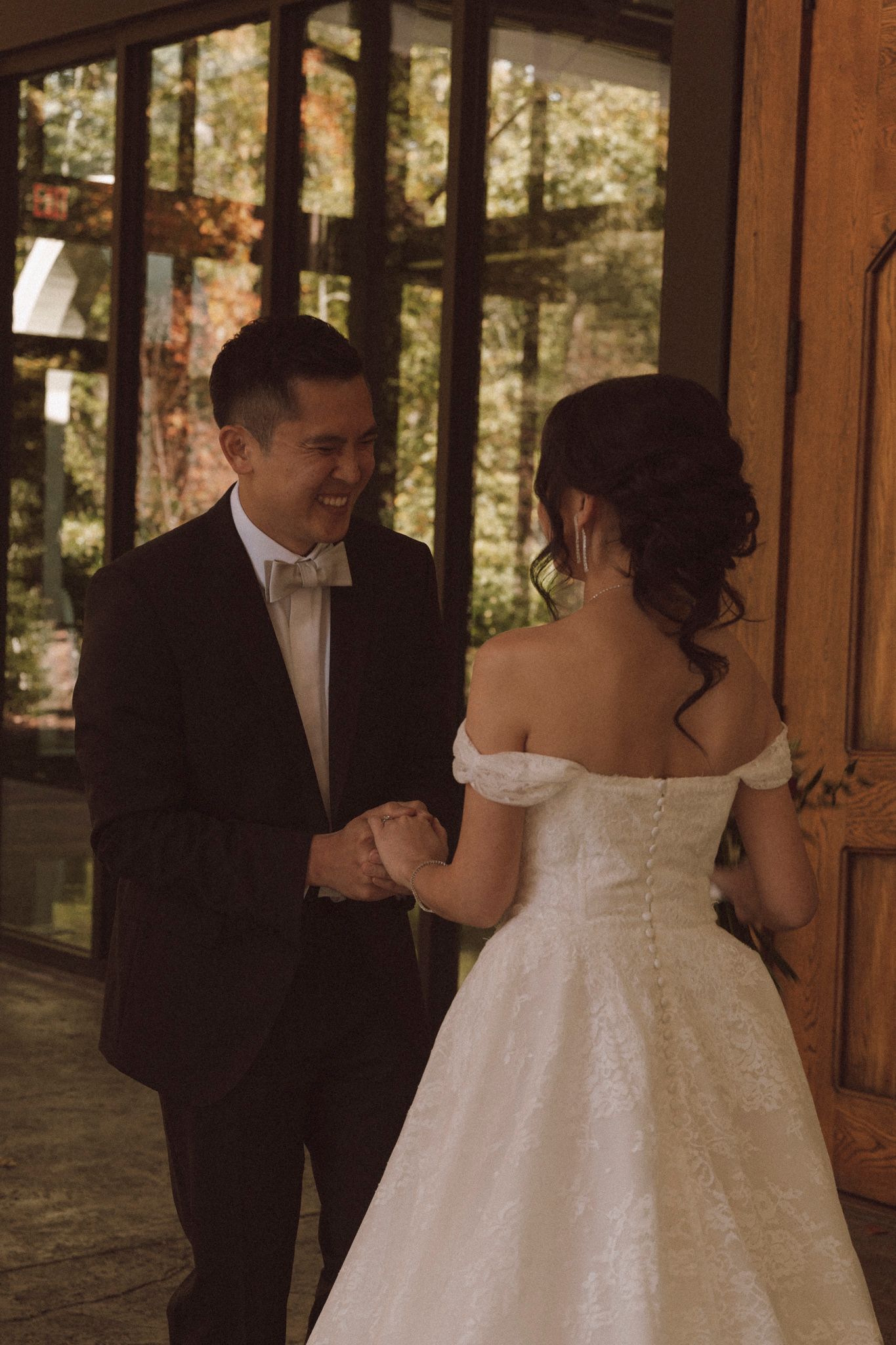 A bride and groom share their first dance together at a rustic indoor wedding venue with wooden walls.