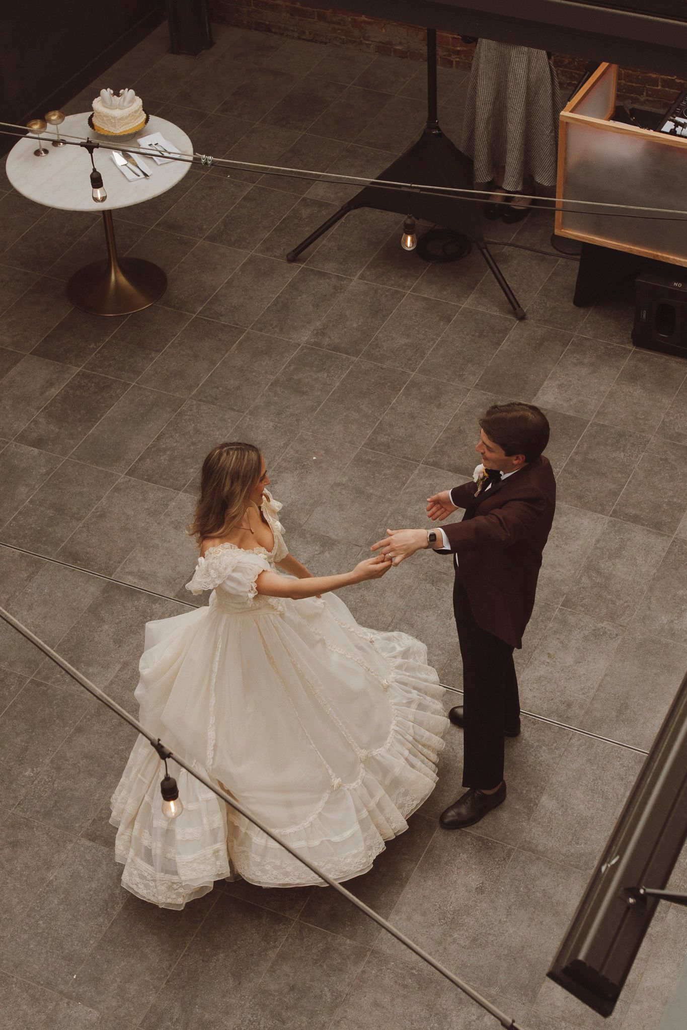 A couple performs a twirling dance move on a stone floor in a wedding celebration sequence.