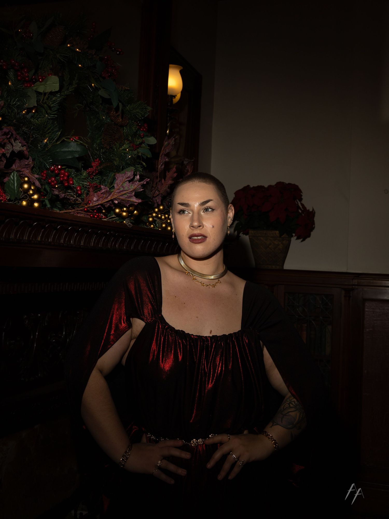 A gothic-styled portrait in dark lighting with red and black velvet clothing against a dim background.