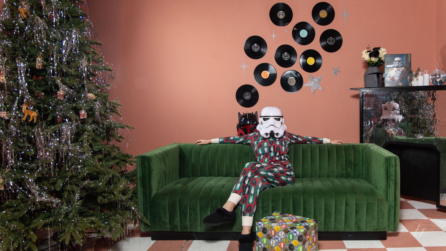 Star Wars Holiday Photos with Green velvet sofa decorated with holiday pillows next to a Christmas tree and vinyl records on a pink wall.