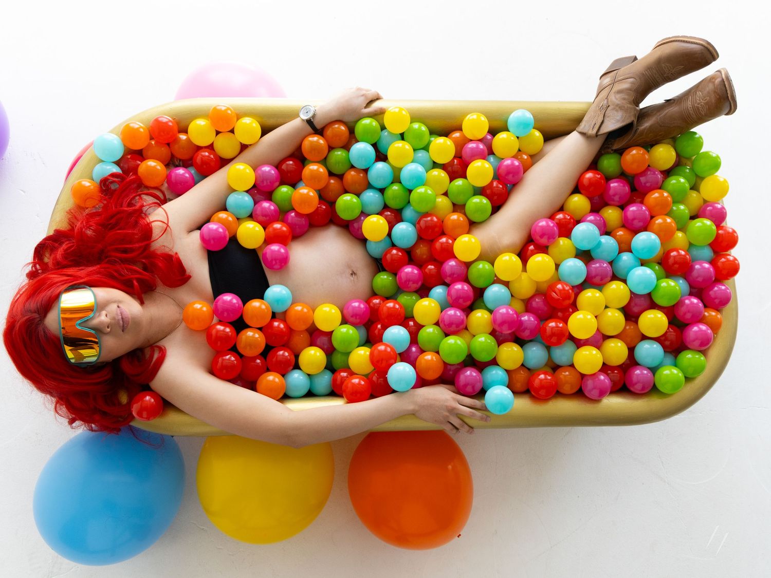 Weird maternity portraits of woman in bathtub of rainbow balls at Denver Photo Collective
