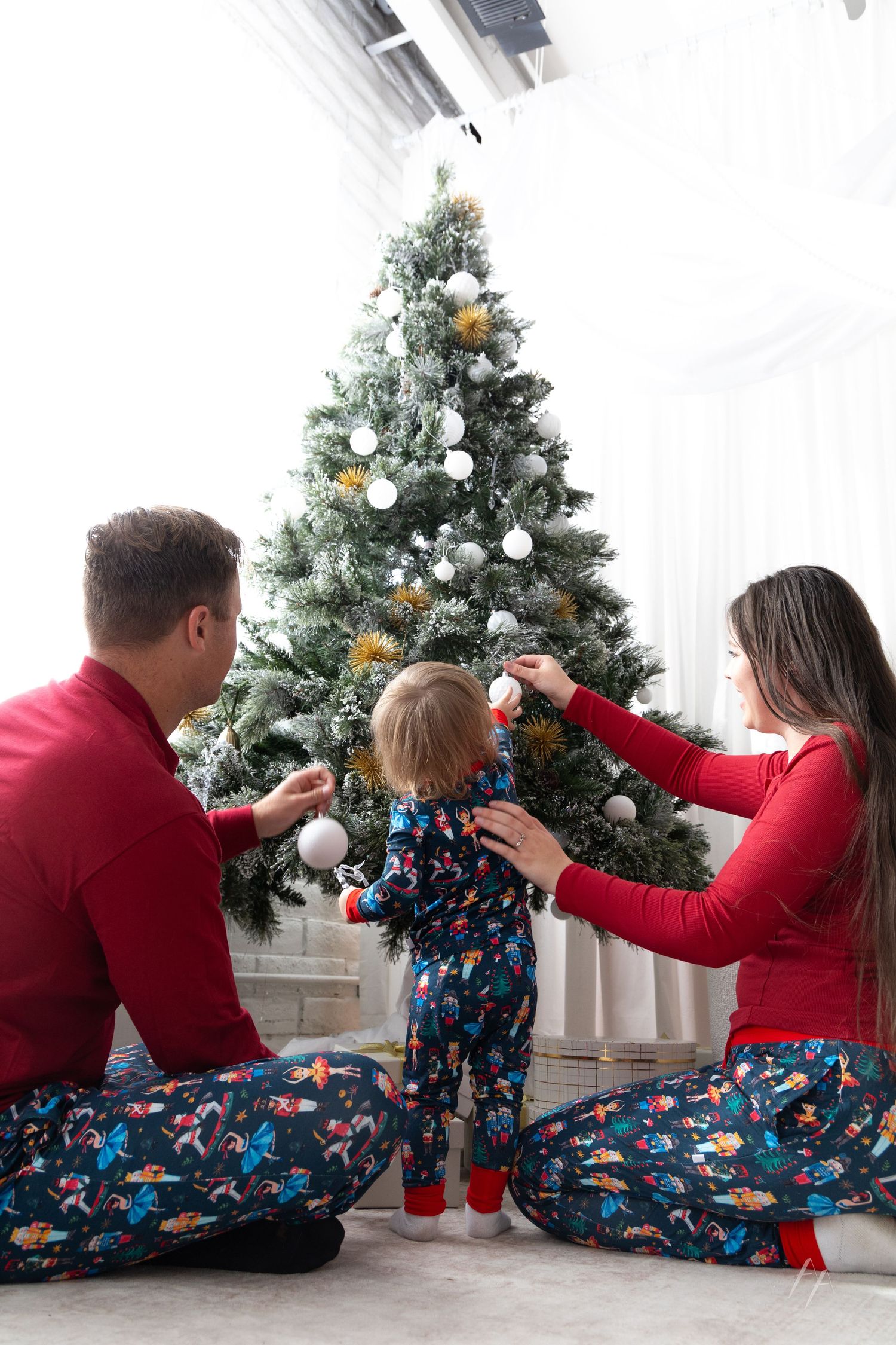 People in matching holiday pajamas pose in sequence while decorating Christmas trees in a festive setting.