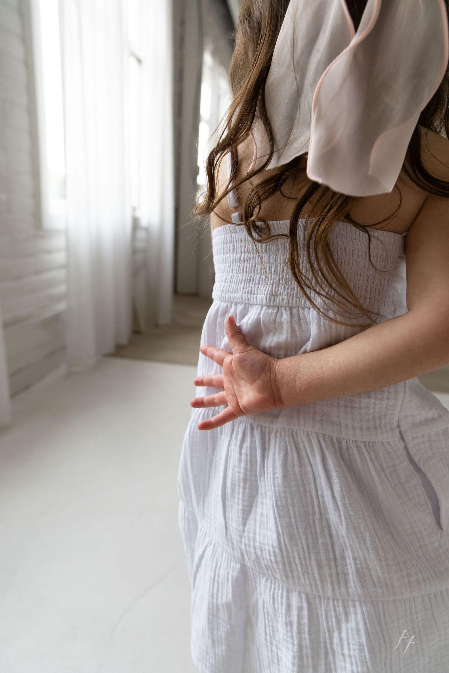 Close-up series showing hands in white linen dress against a bright window backdrop.