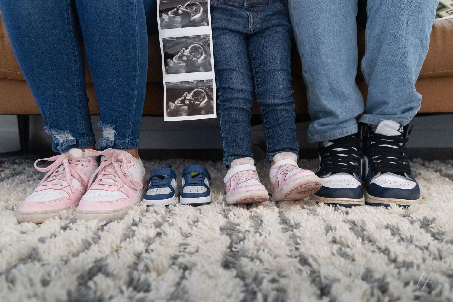 A collection of different sneakers and shoes shown side by side on a textured carpet surface.