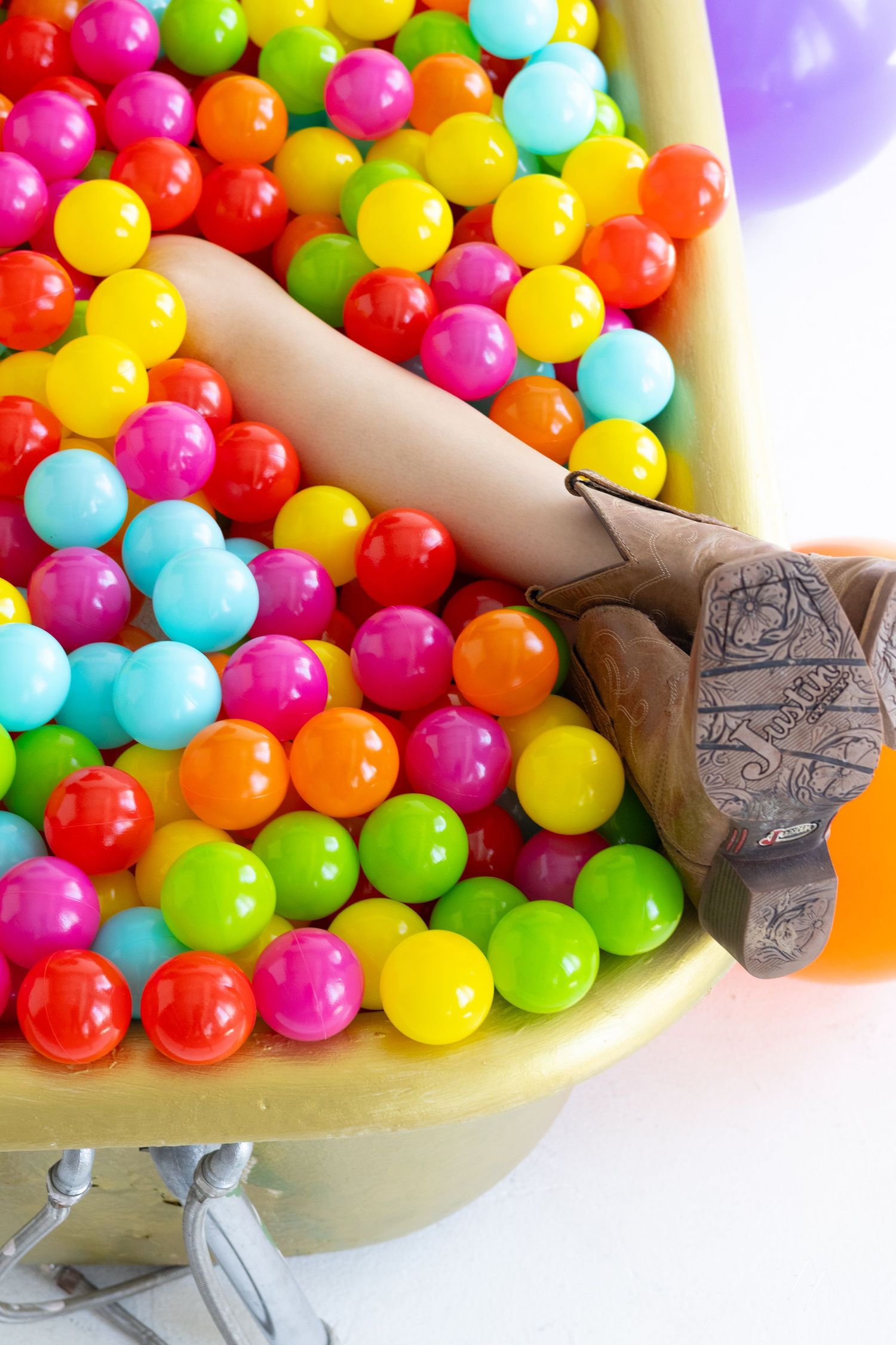Weird maternity portraits of woman in bathtub of rainbow balls at Denver Photo Collective