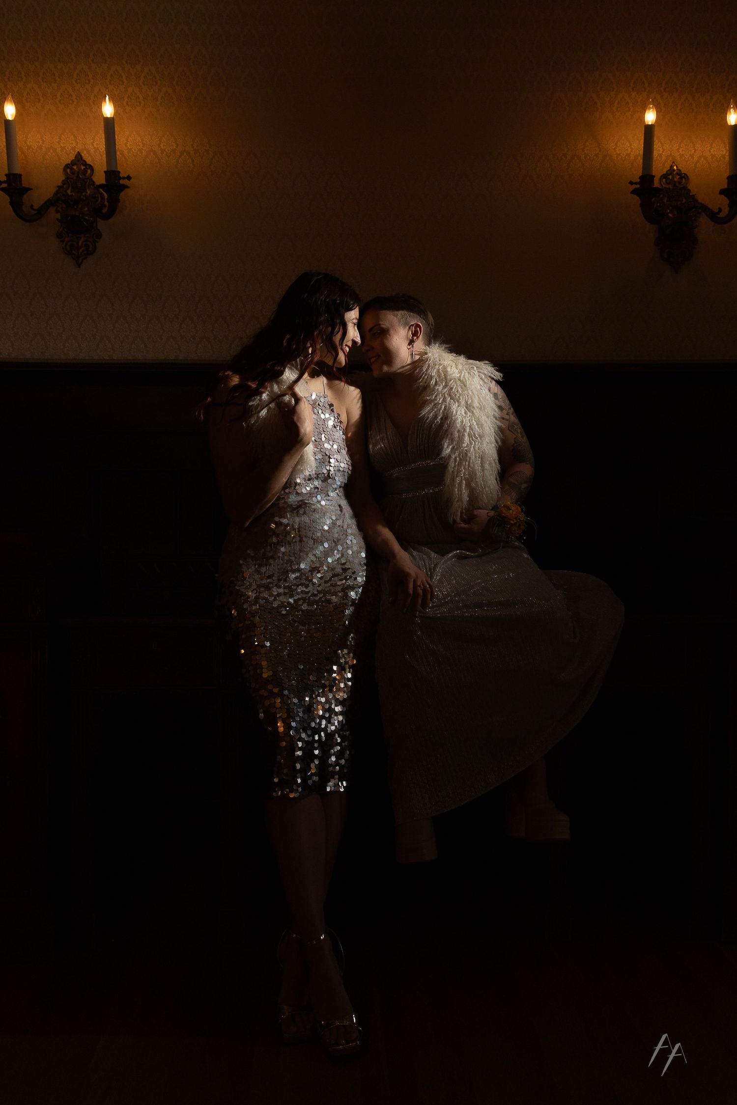A couple dances together in a dimly lit ballroom with romantic candlelight ambiance in the background.