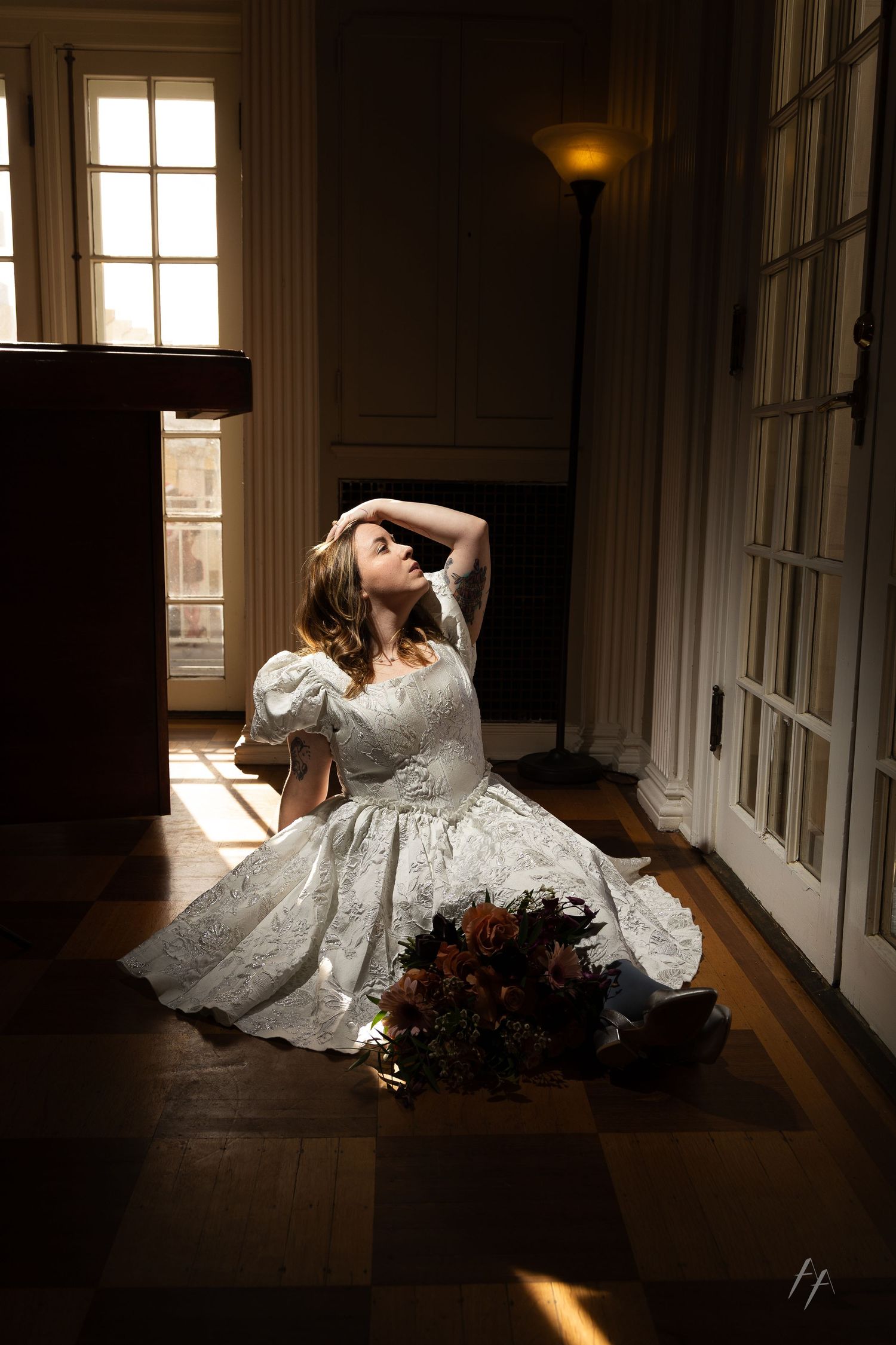 A dramatic bridal portrait series with a white lace gown against sunlit windows in an elegant hallway.