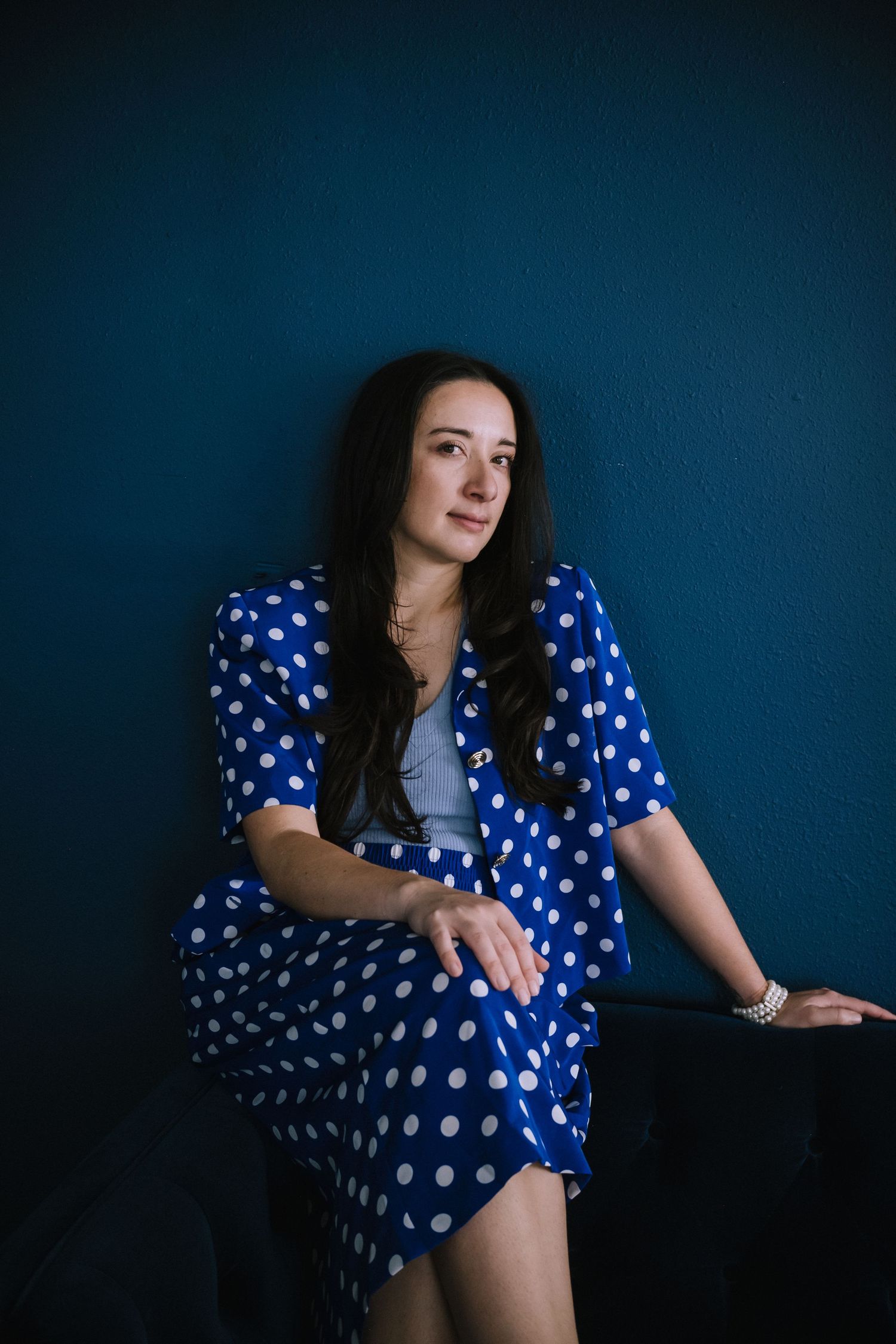 A polka dot blue dress against a deep blue wall creates a striking contrast. Denver Photo Collective