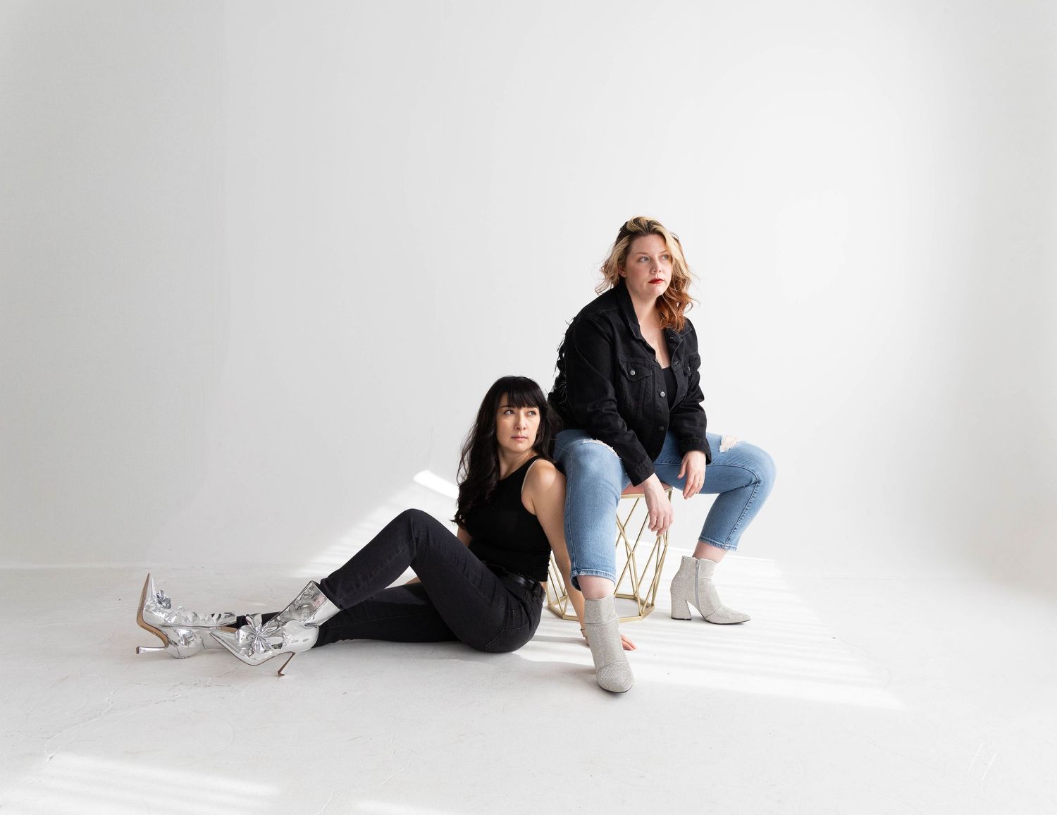Person in black outfit lying on white floor in various artistic poses against minimalist studio background.