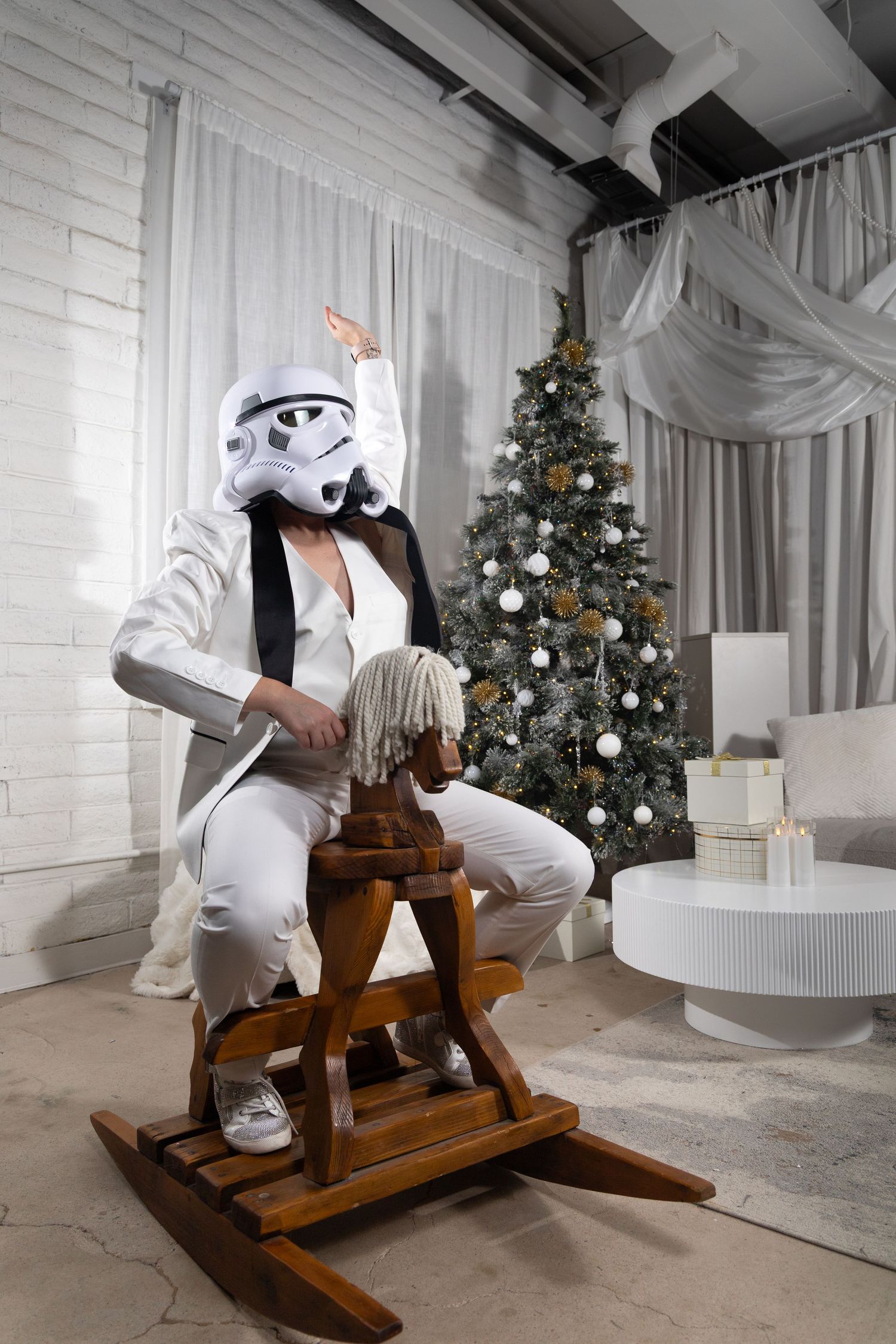 Holiday photos with wooden rocking horse and decorated Christmas trees in white studio setting.