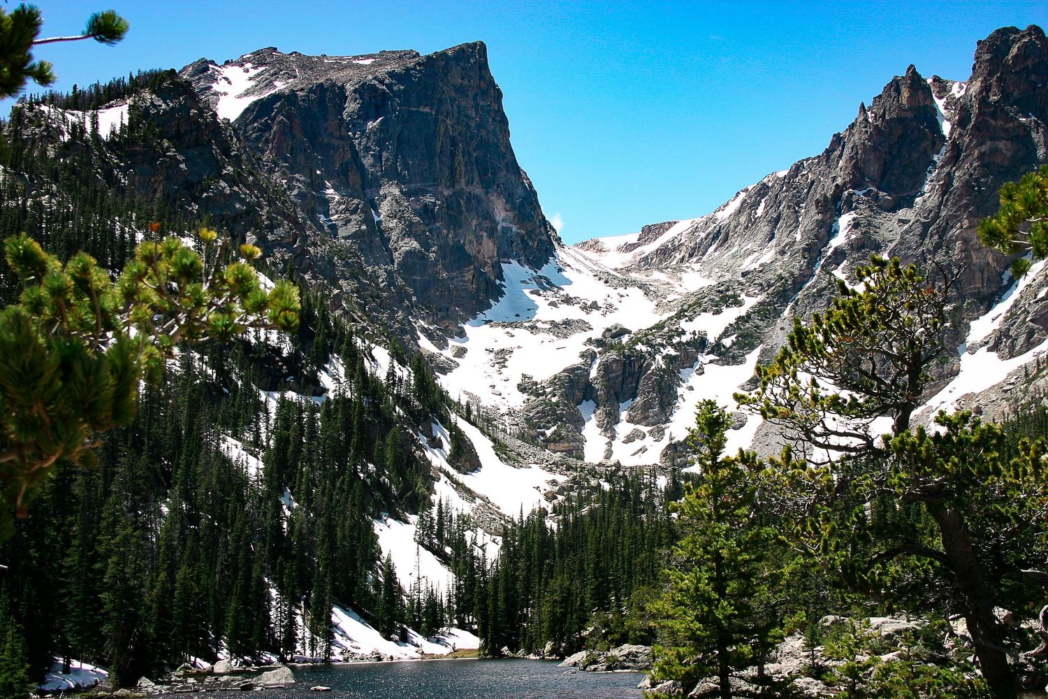 Majestic Rocky Mountain peaks with snow patches against bright blue sky. Rocky Mountain National Park