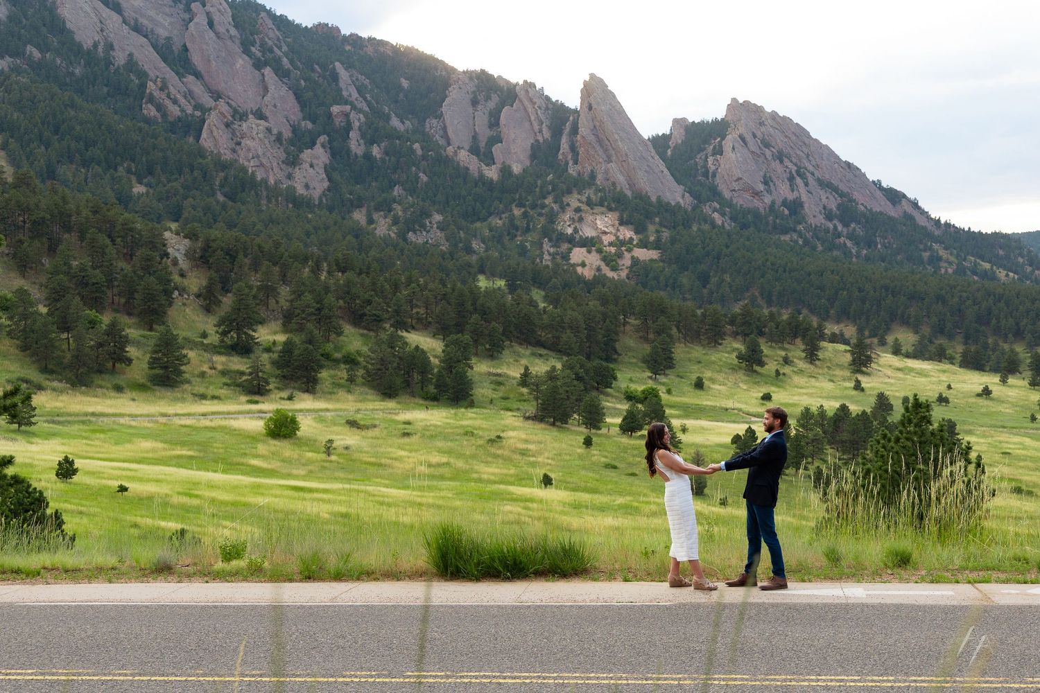 Scenic mountain backdrop with grassy field and figures in silhouette against the Flatirons.
