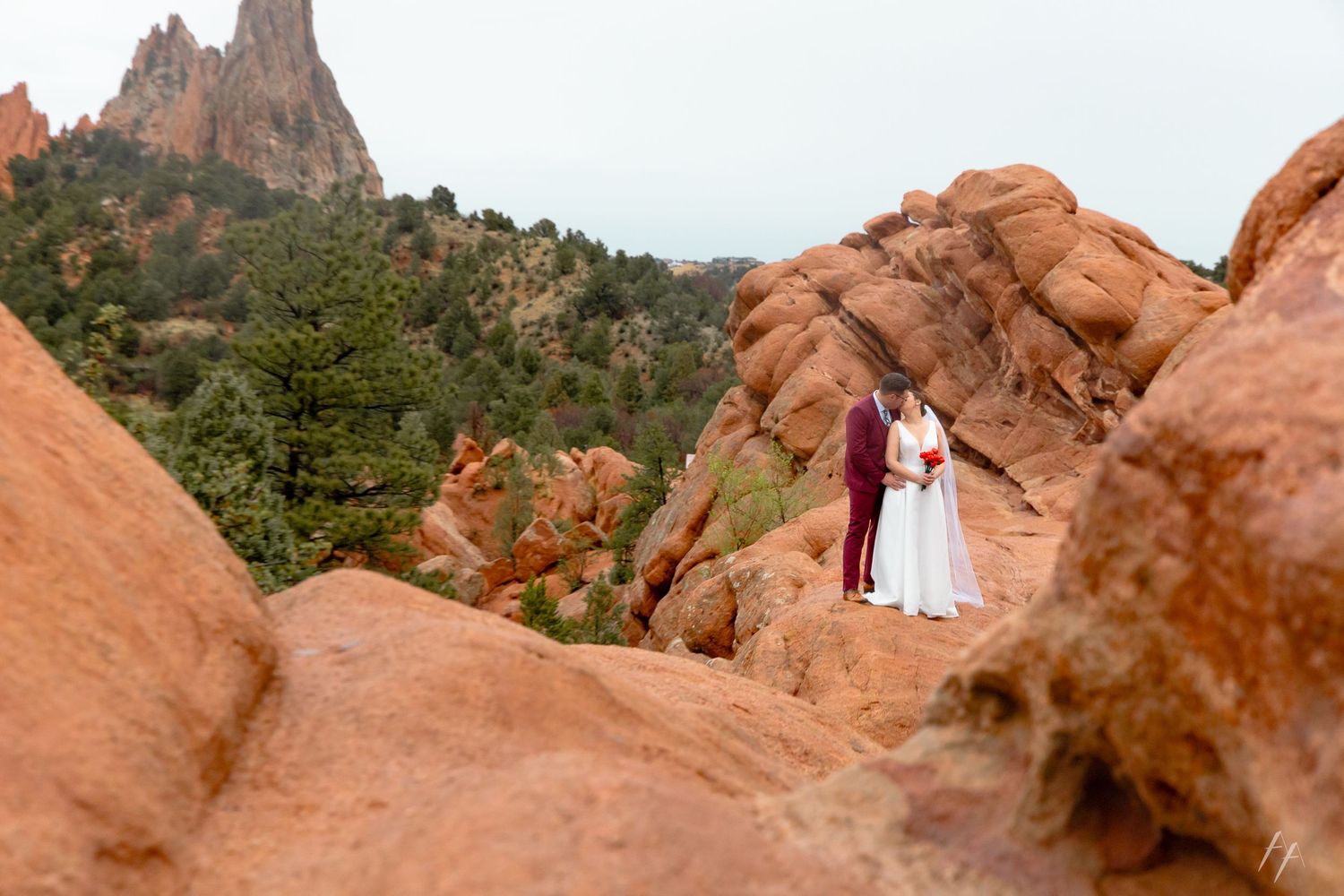 People exploring scenic red rock formations at Garden of the Gods park in Colorado Springs against a blue sky.