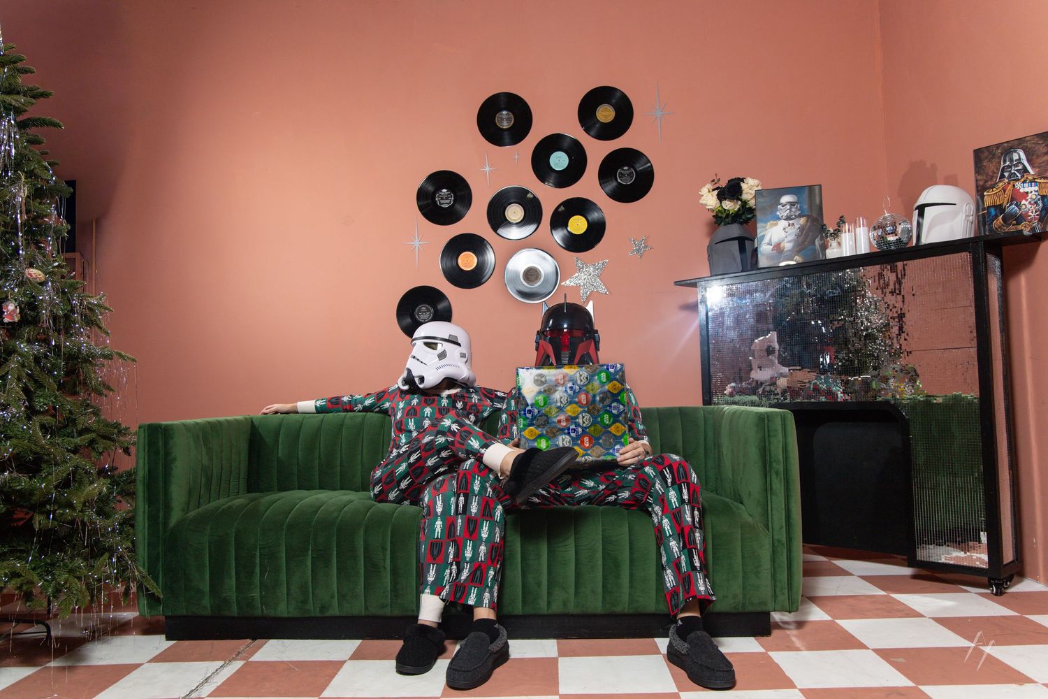 Star Wars Holiday Portraits in A retro-styled room features pink walls, vinyl records as decor, and an emerald green velvet sofa.