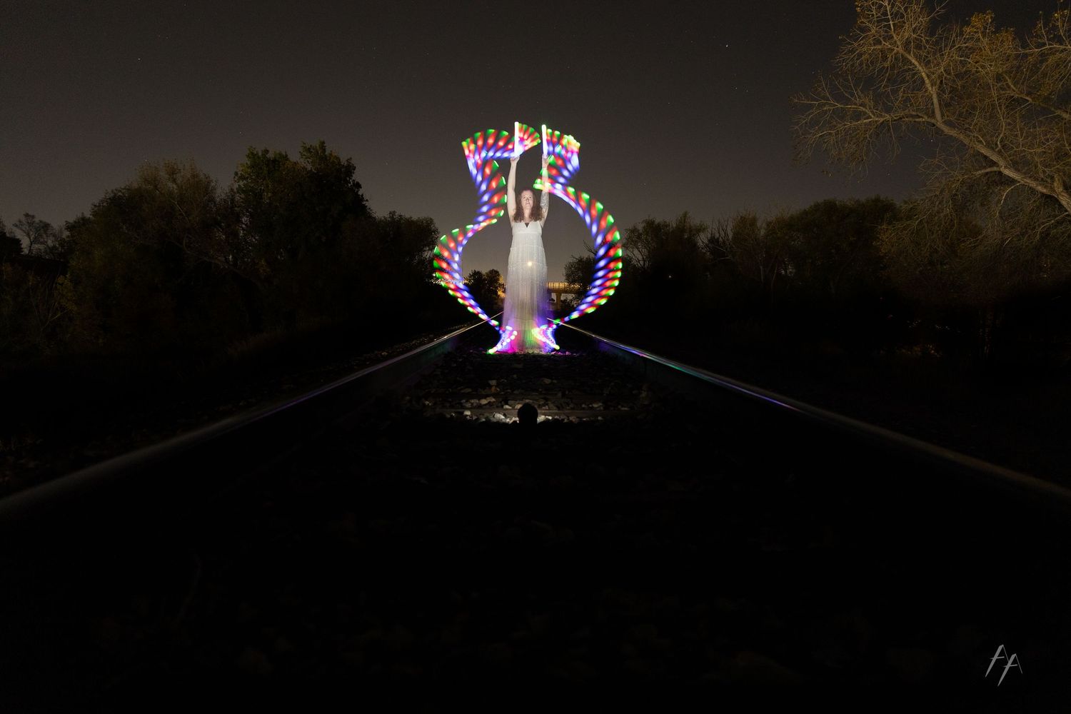 A series of illuminated architectural structures and lights at night creating a glowing display in a dark setting.