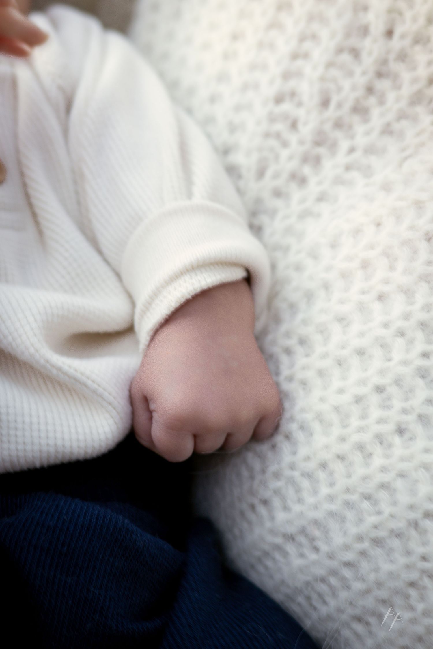 Close-up series of a person's hand in a white knit sweater resting on a textured white surface.
