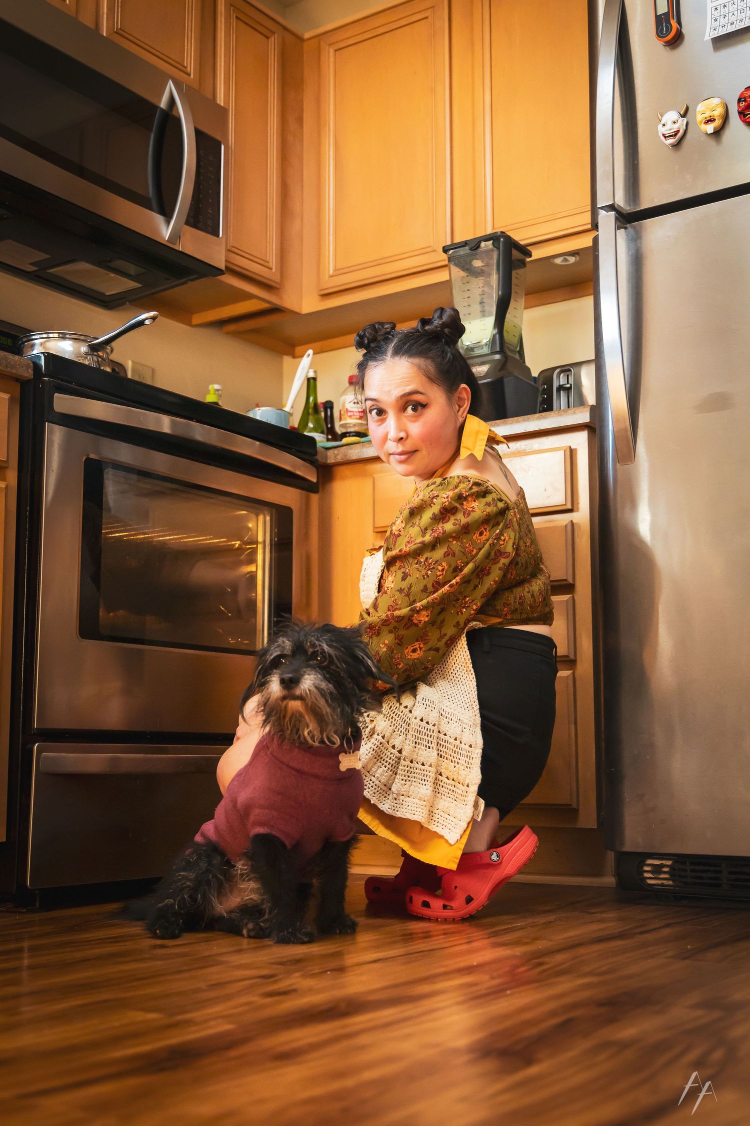 Person checking under kitchen cabinets with warm lighting and hardwood floors.