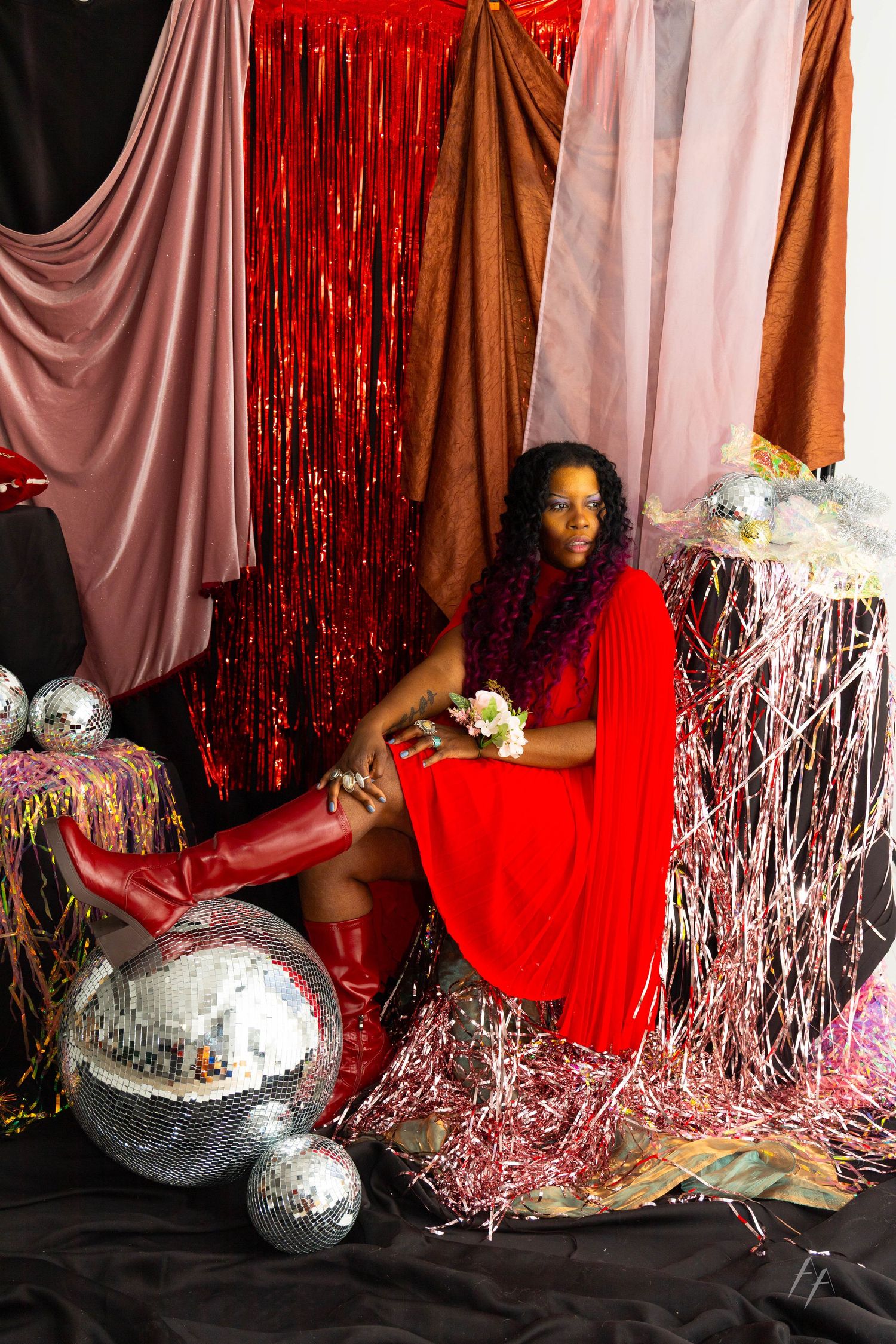 Disco-themed party setup with silver disco balls, red tinsel curtains, and white fabric draping creates a festive atmosphere.
