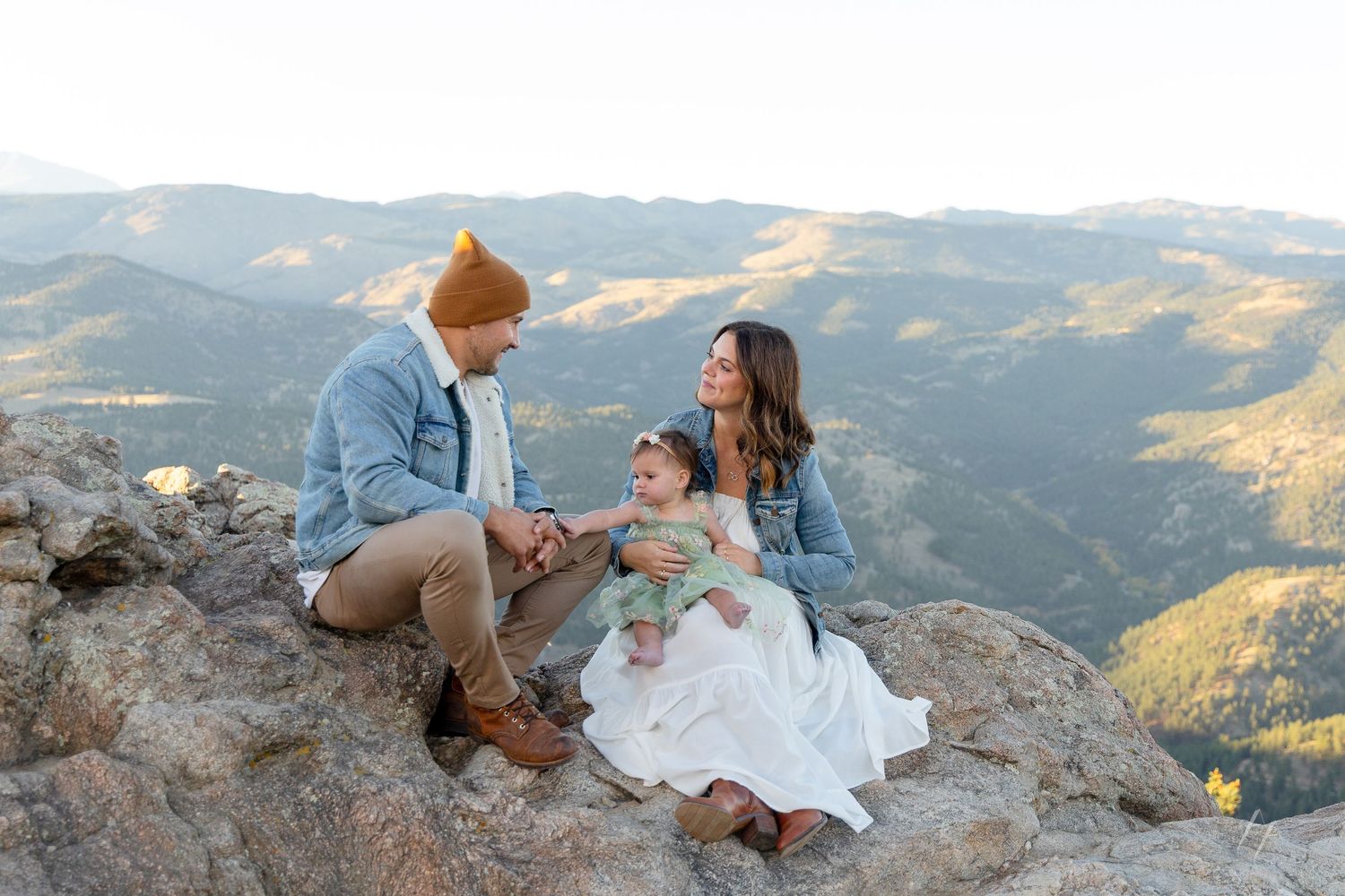 A couple in wedding attire shares an intimate moment on a scenic mountain overlook at sunset.