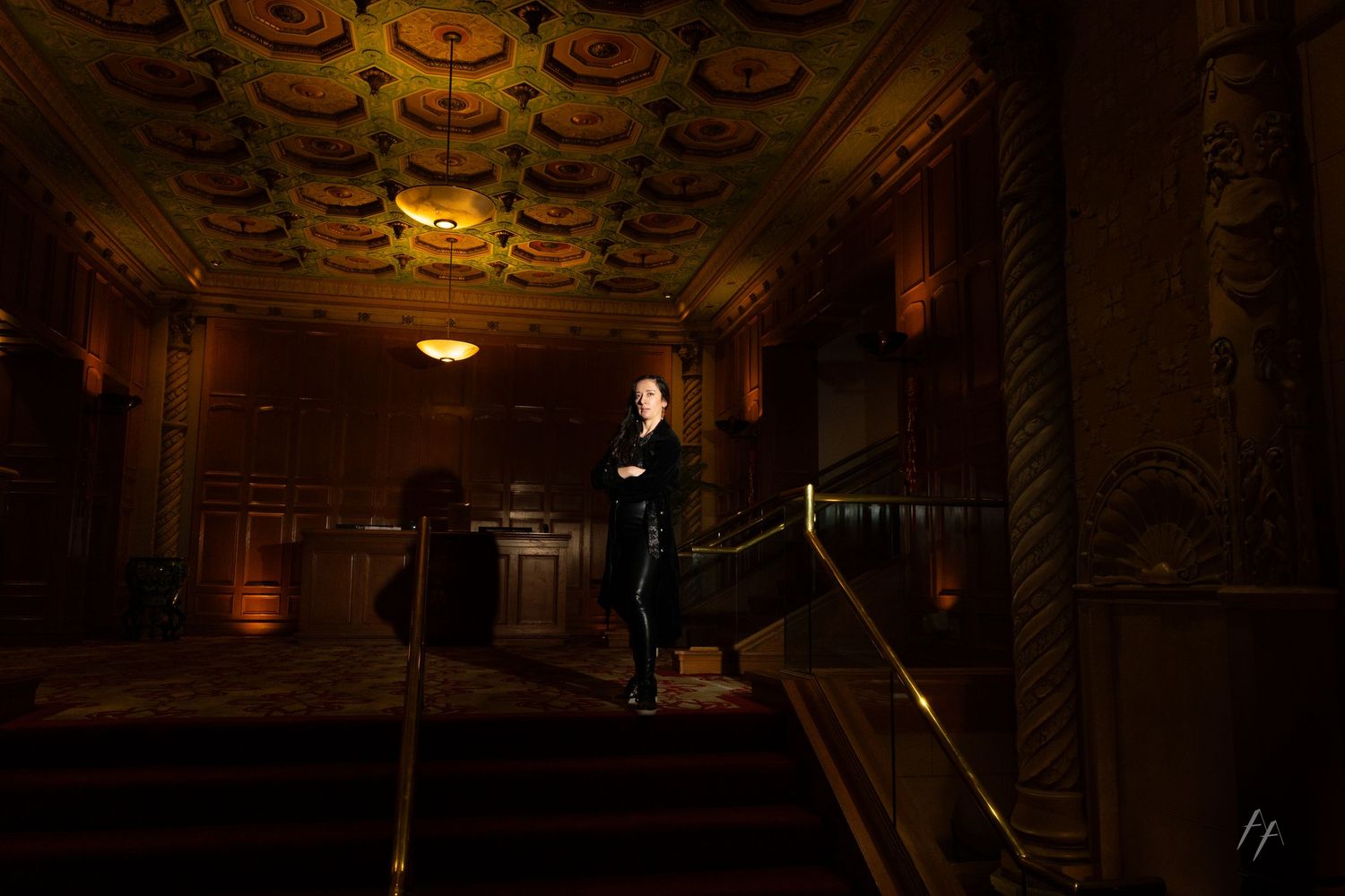 Ornate theater interior with golden decorative ceiling and dramatic lighting creates an elegant ambiance.